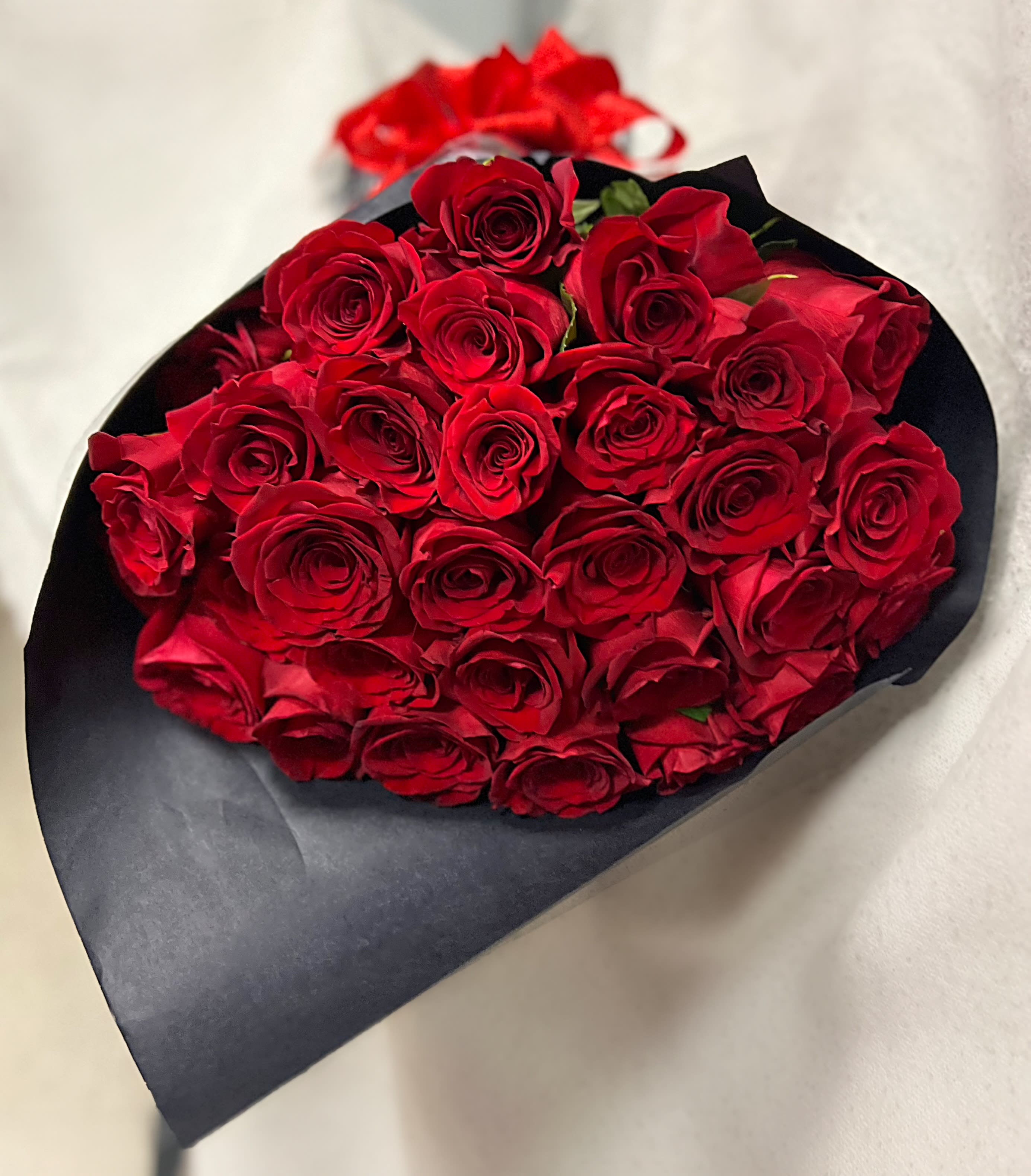 Bouquet of red roses wrapped in black paper with a red ribbon