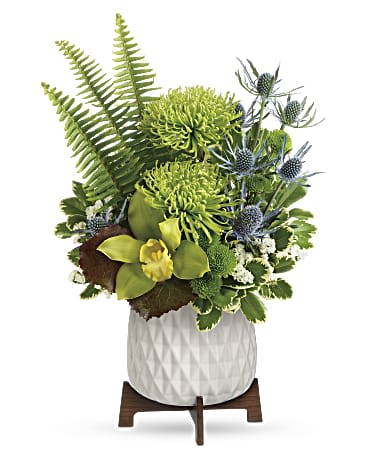 Green floral arrangement in a white textured pot on a wooden stand