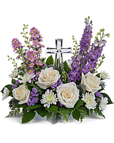White roses and purple flowers arranged around a silver cross