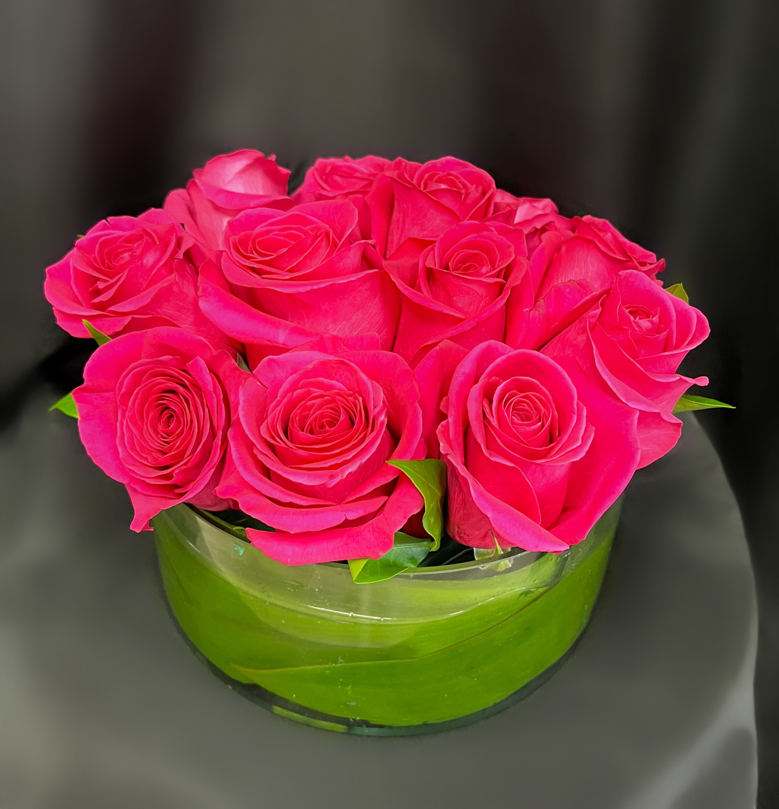 Bright pink roses arranged in a low round glass bowl