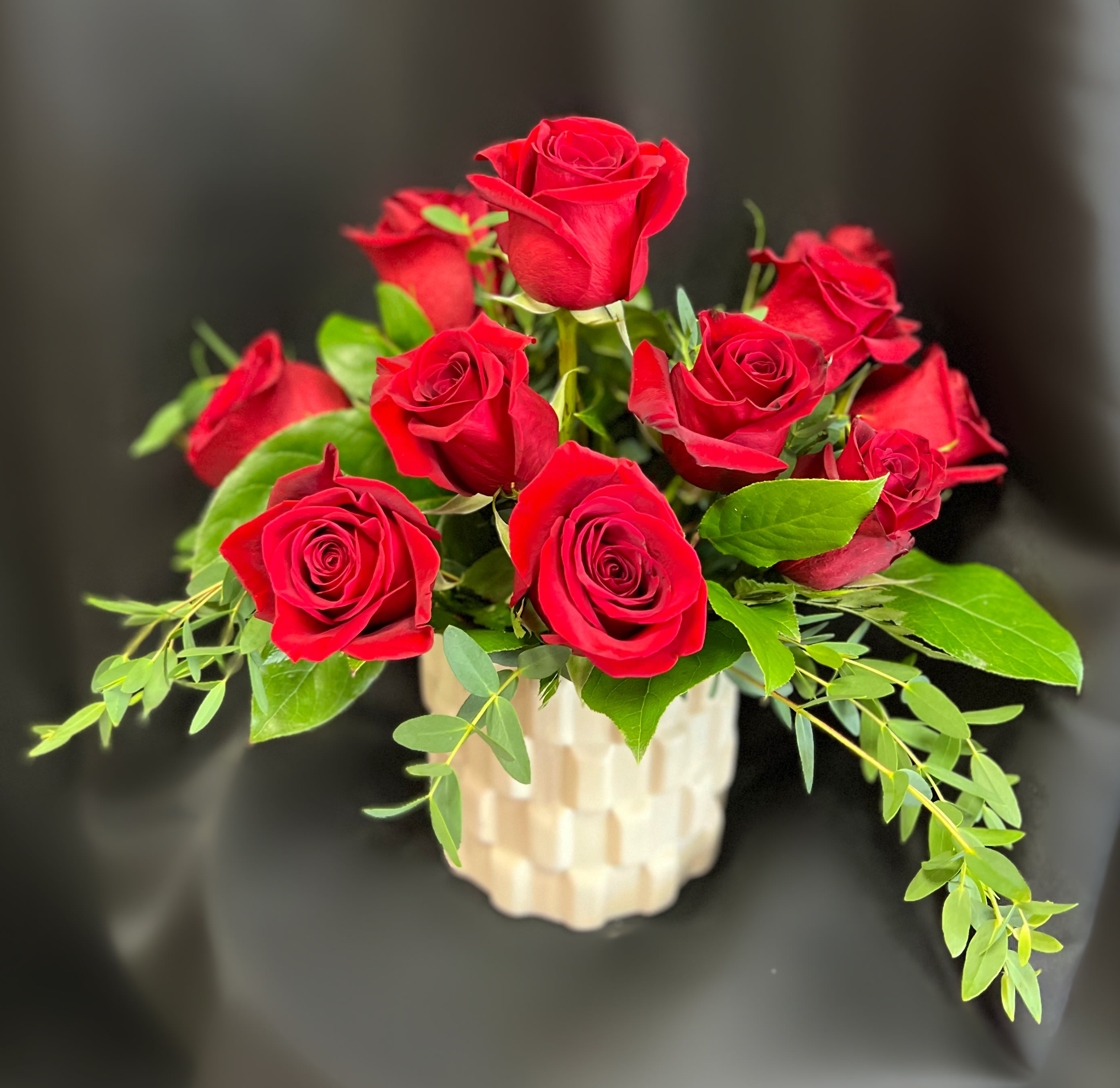Red roses arranged in a cream textured vase