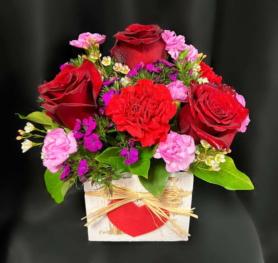 Red roses and pink carnations in a white wooden box with a red heart
