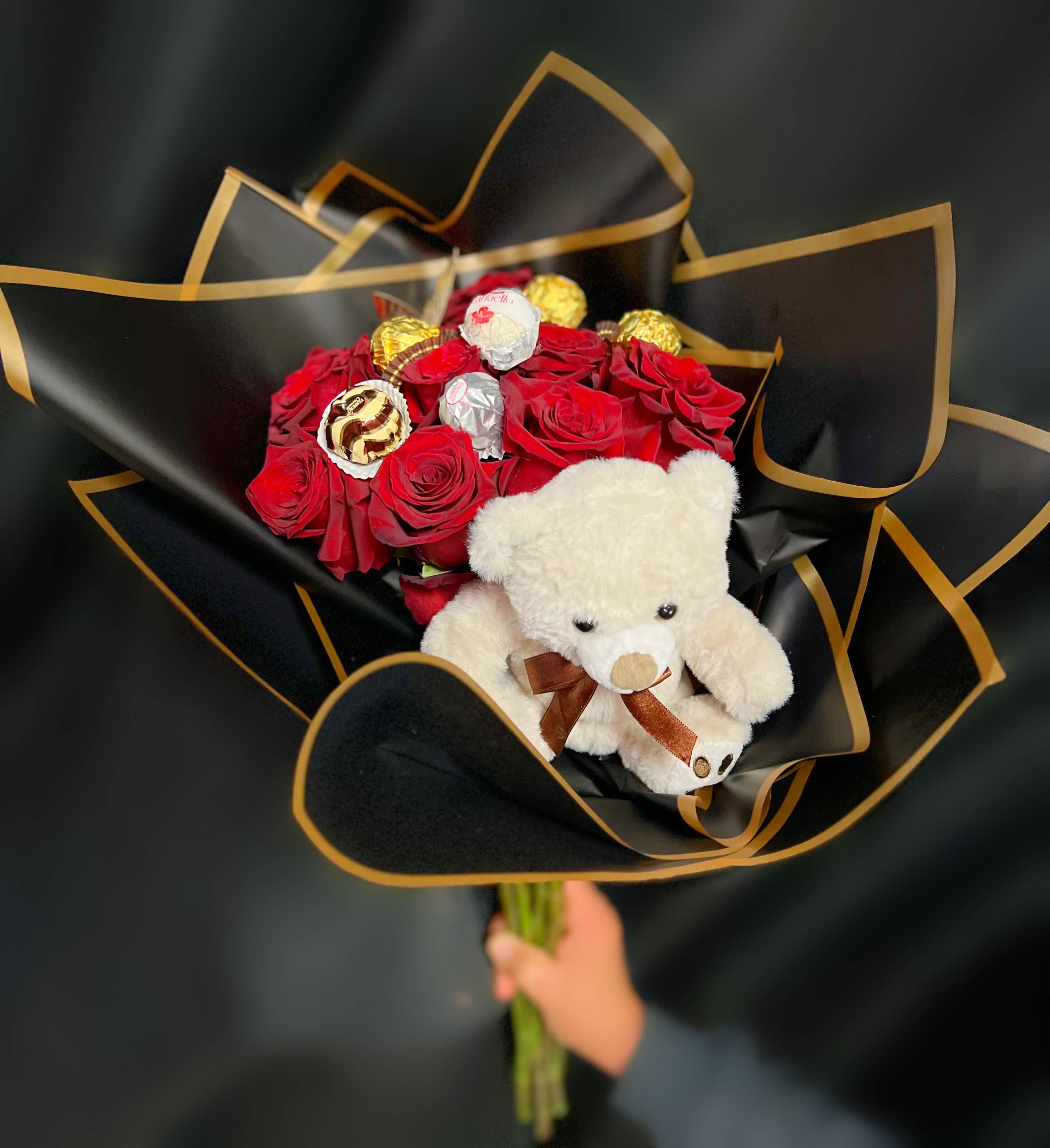 Red rose bouquet with chocolates and a teddy bear in black wrap