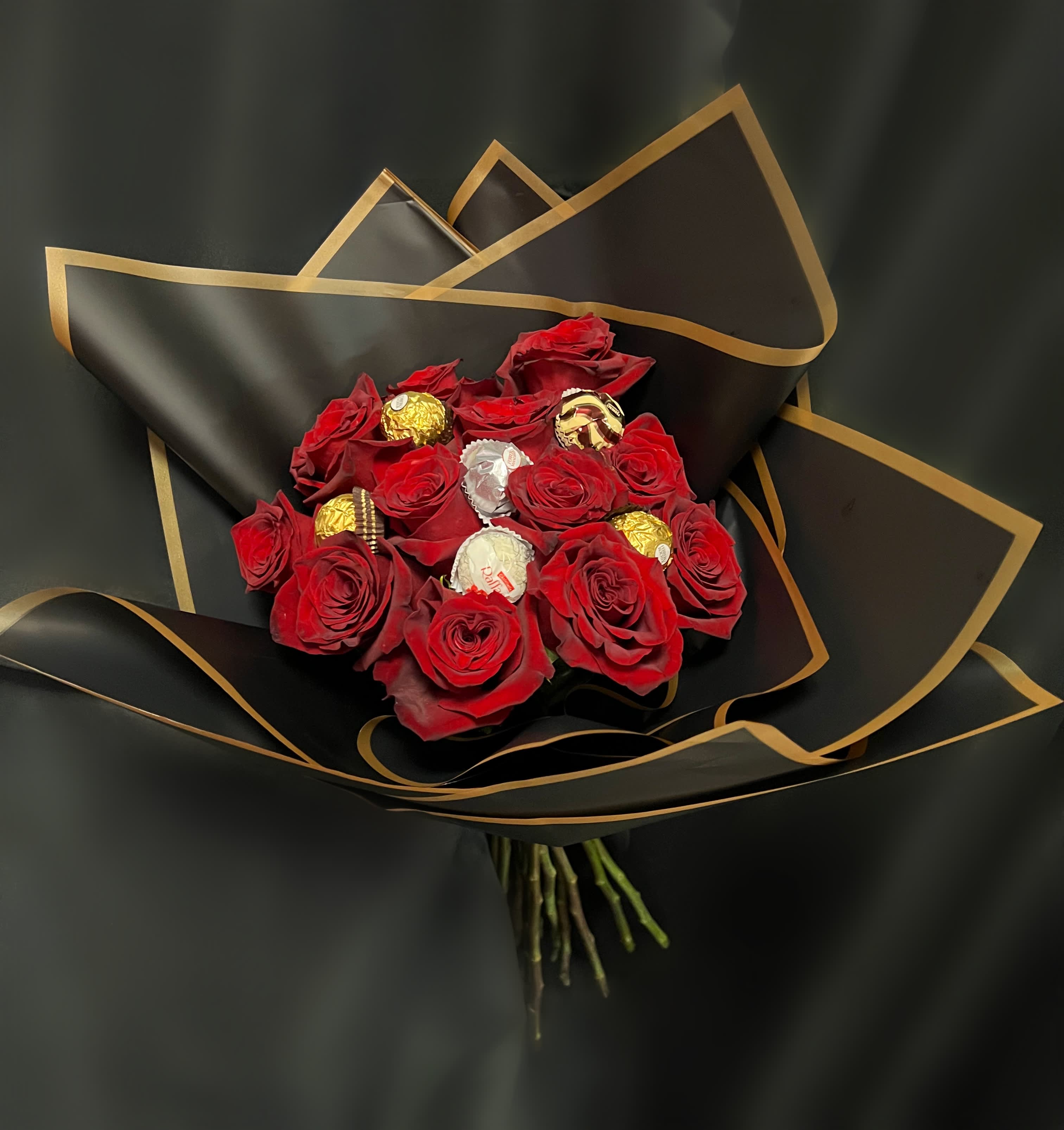 Red rose bouquet with assorted chocolates wrapped in black paper with gold trim