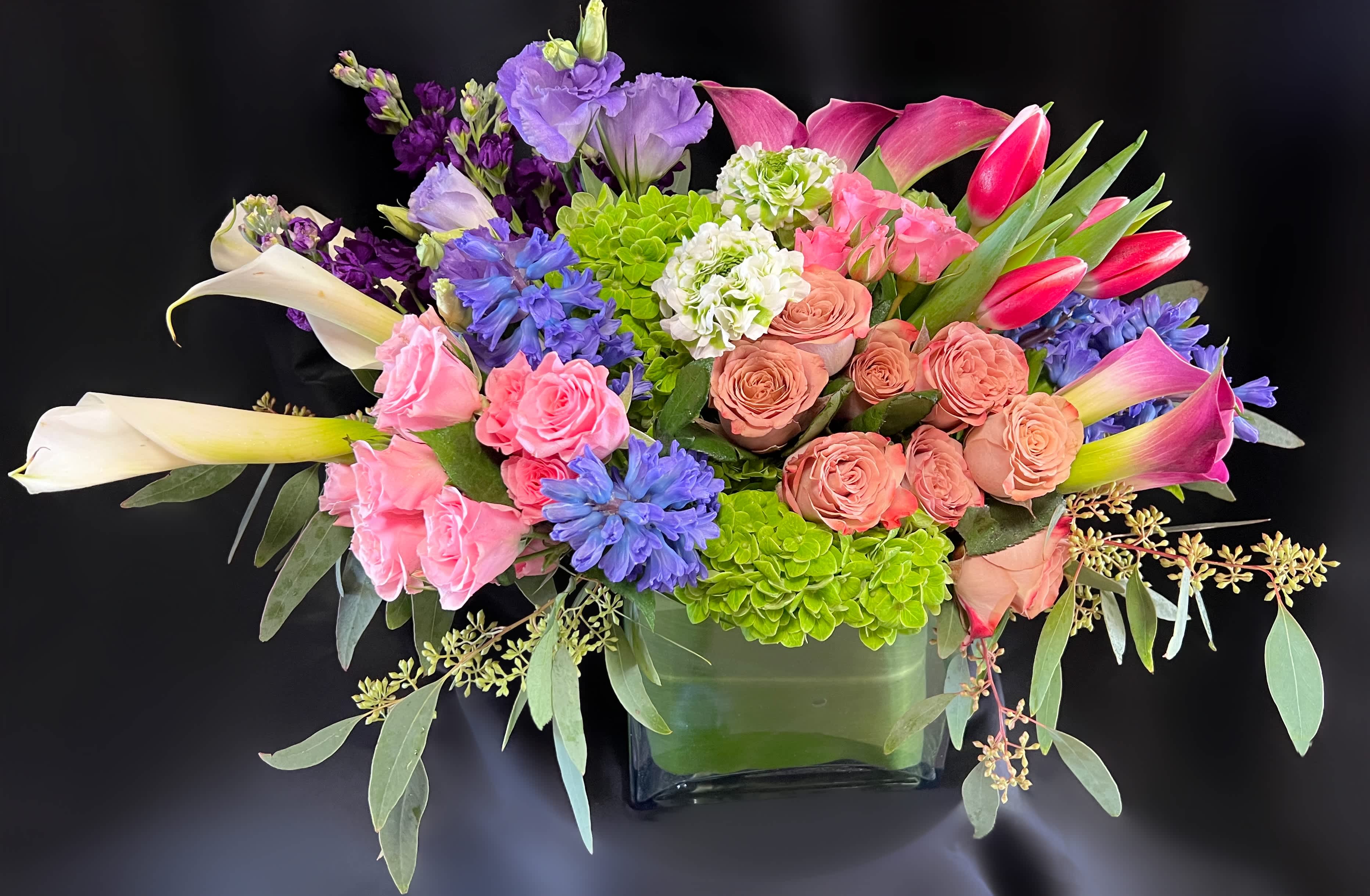 Colorful mixed flower arrangement in a square glass vase