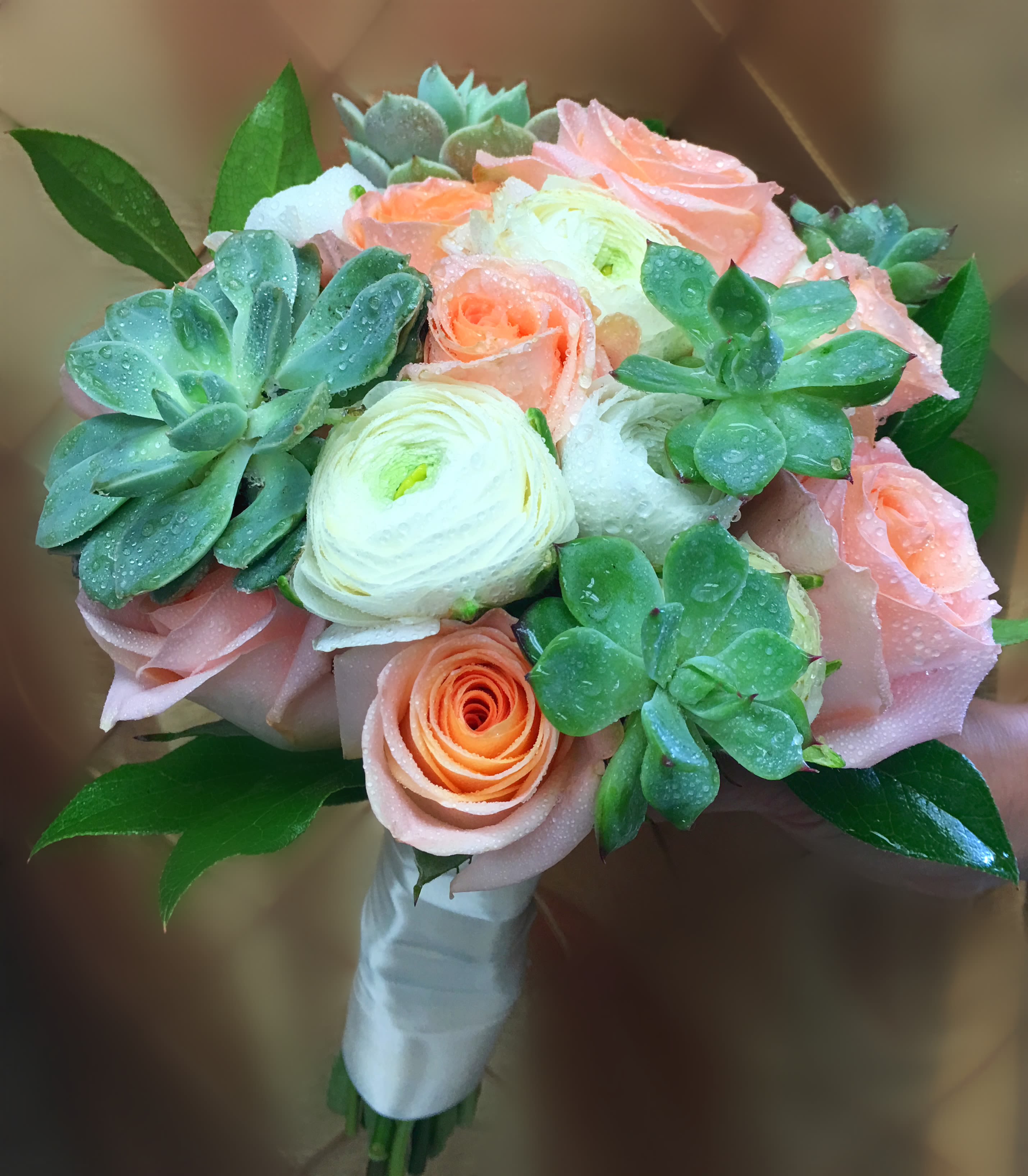 Bouquet of peach roses and white ranunculus with succulents