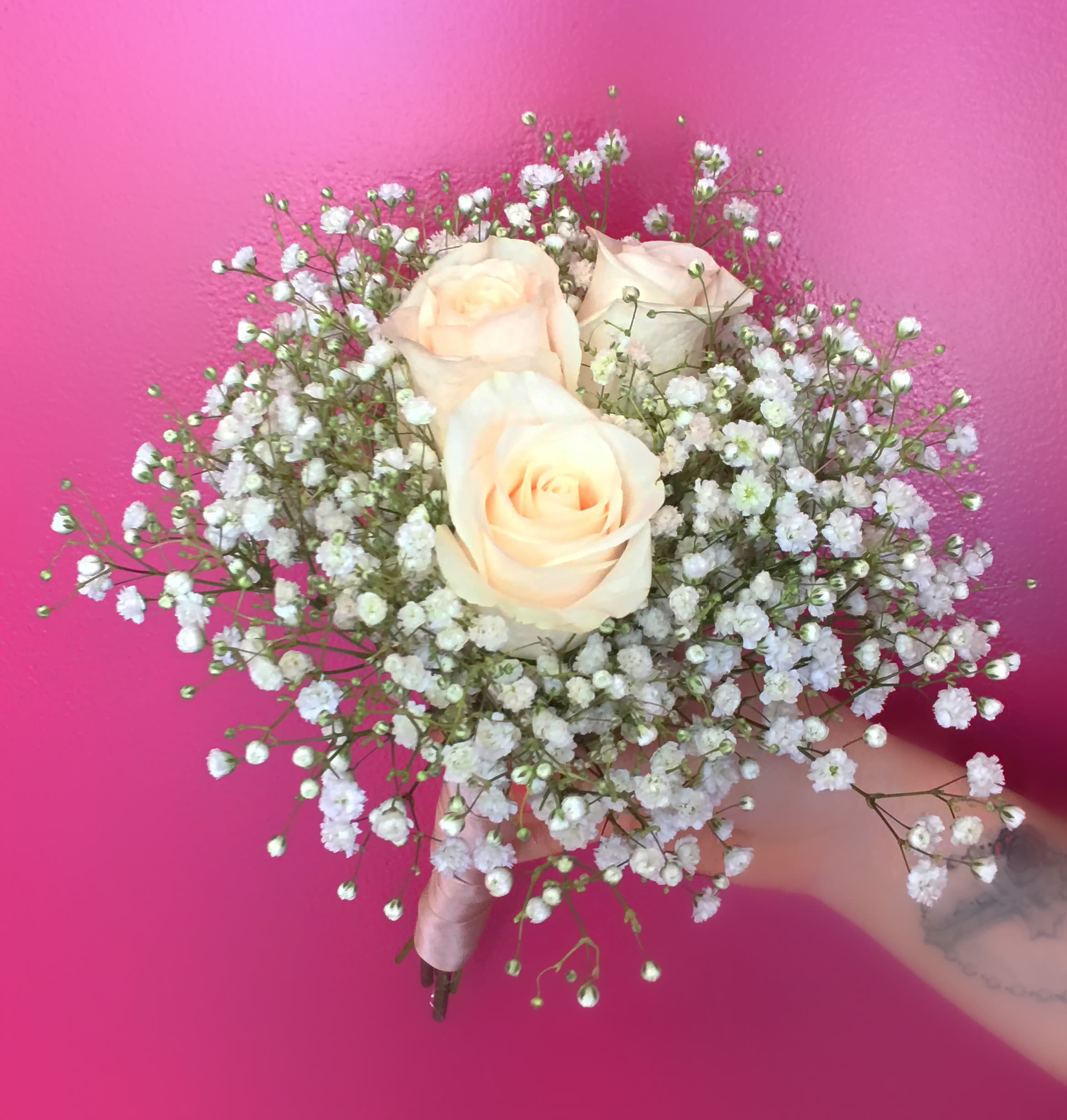 Handheld bouquet of pale peach roses and white baby's breath
