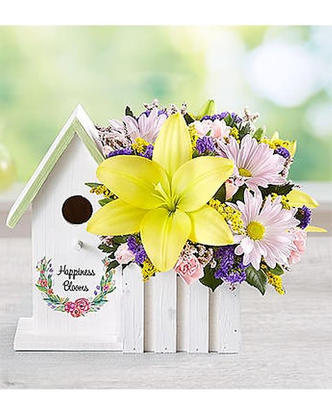 Bouquet with a large yellow lily and pastel daisies beside a white birdhouse
