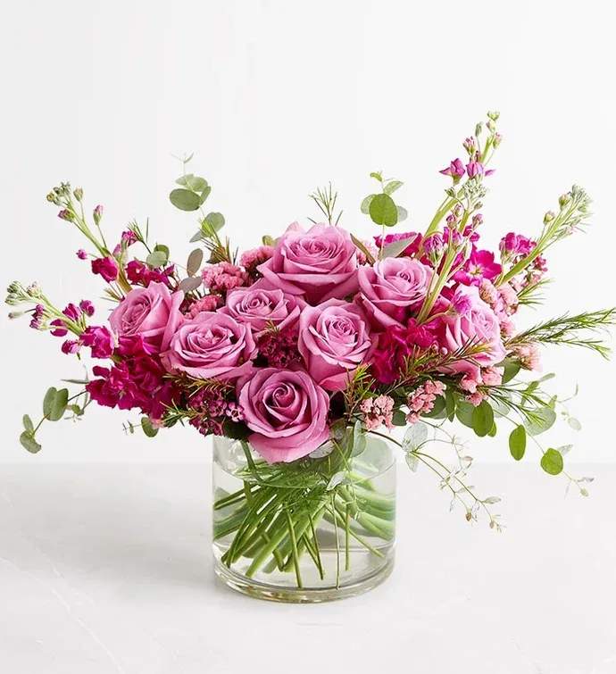 Pink roses arranged in a clear glass vase with small magenta filler flowers