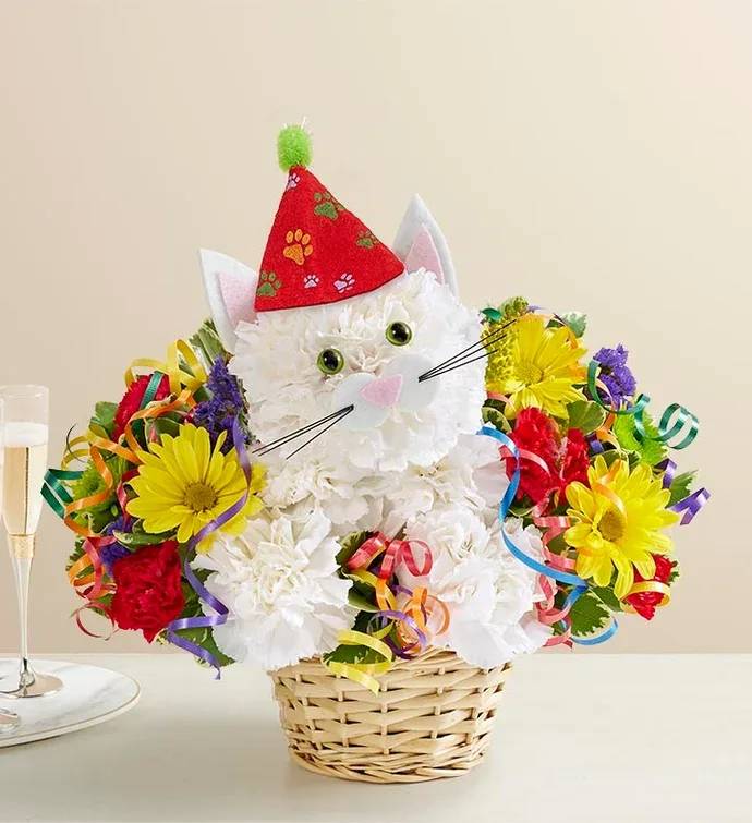 Cat-shaped flower arrangement in a wicker basket with a party hat