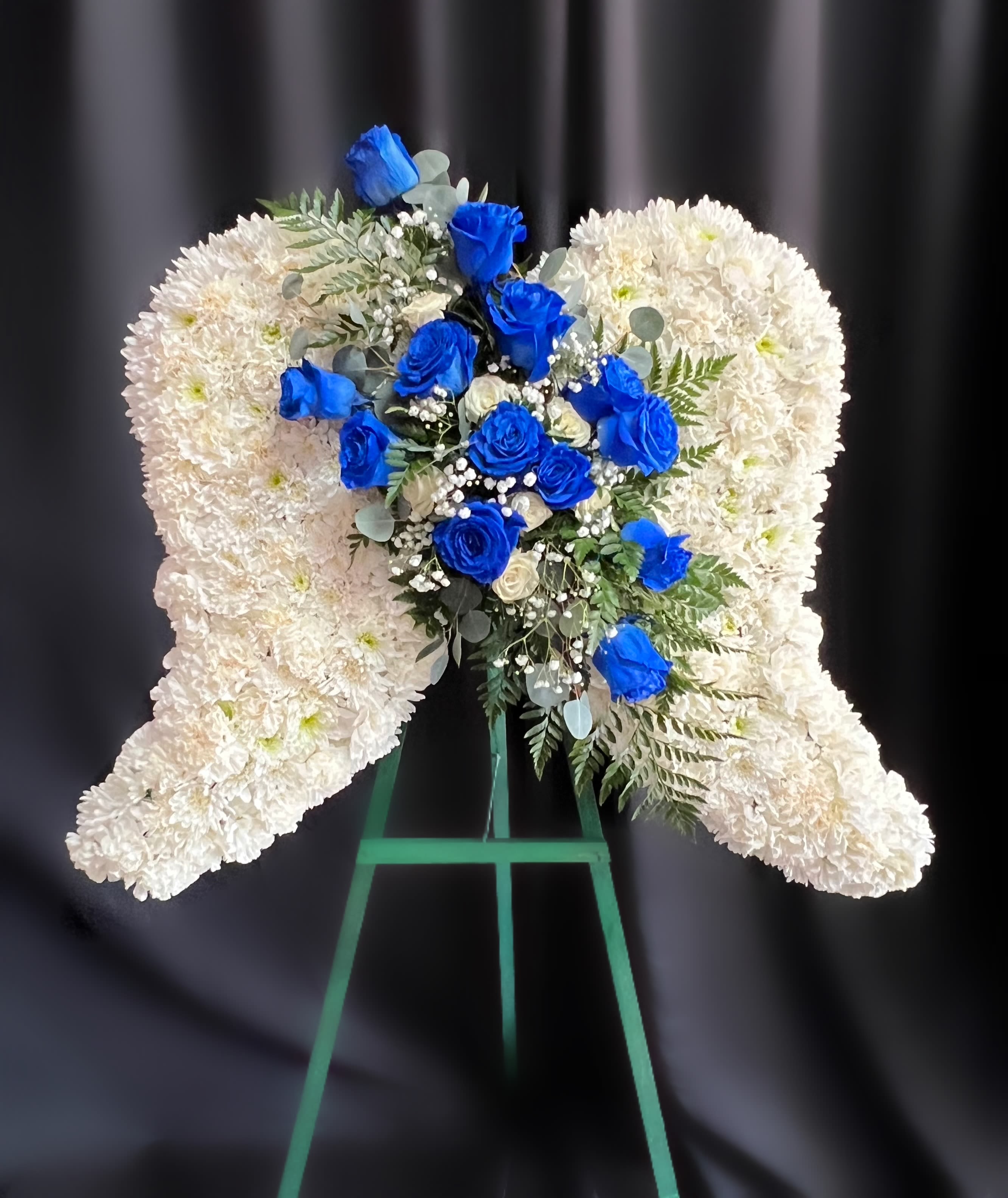 White floral heart wreath with blue roses on a stand