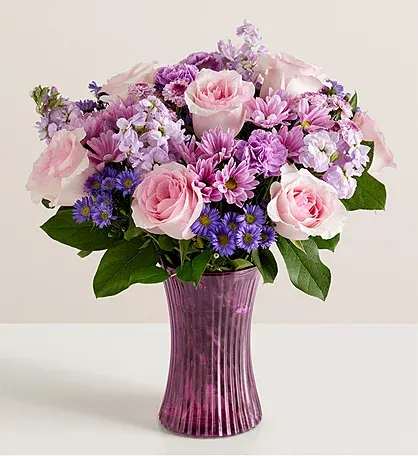 Pink and purple mixed bouquet in a purple glass vase