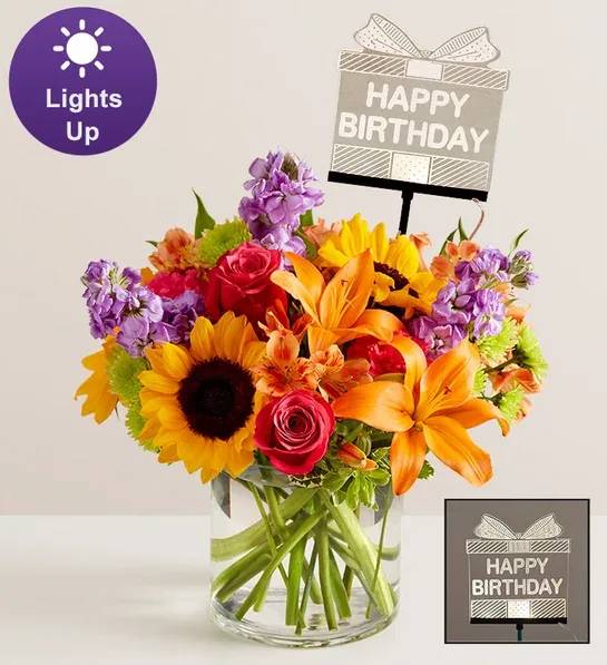 Bright mixed bouquet in a glass vase with a birthday sign