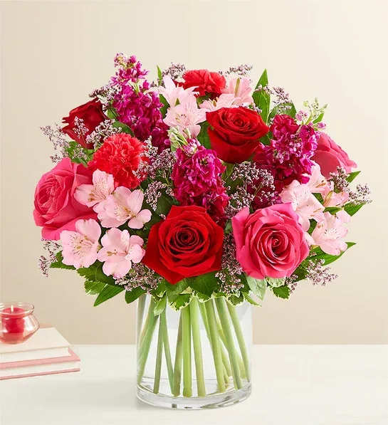 Bouquet of red and pink roses with pale pink flowers in a glass vase