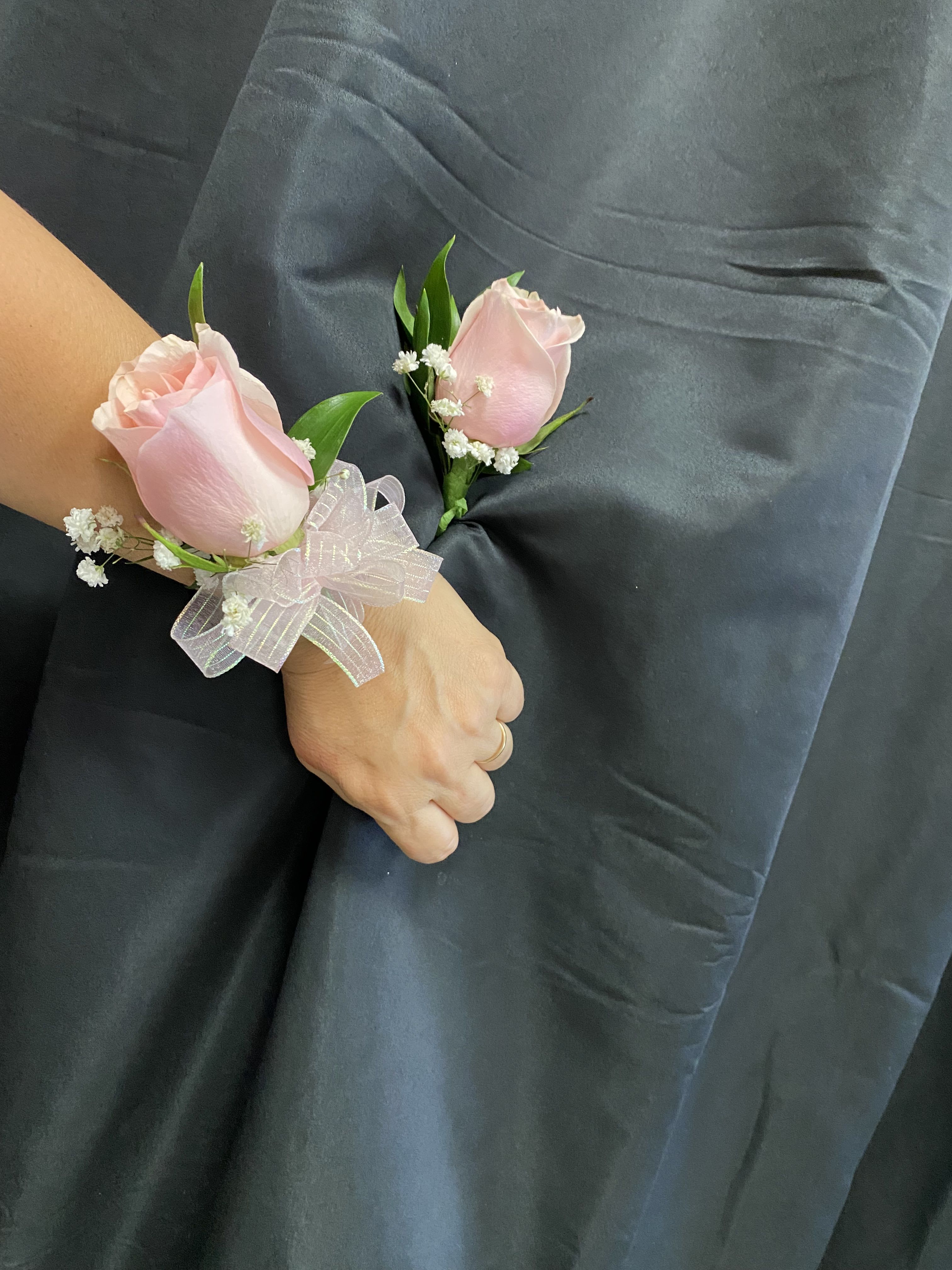 Two pink rose corsages with white baby's breath and ribbon