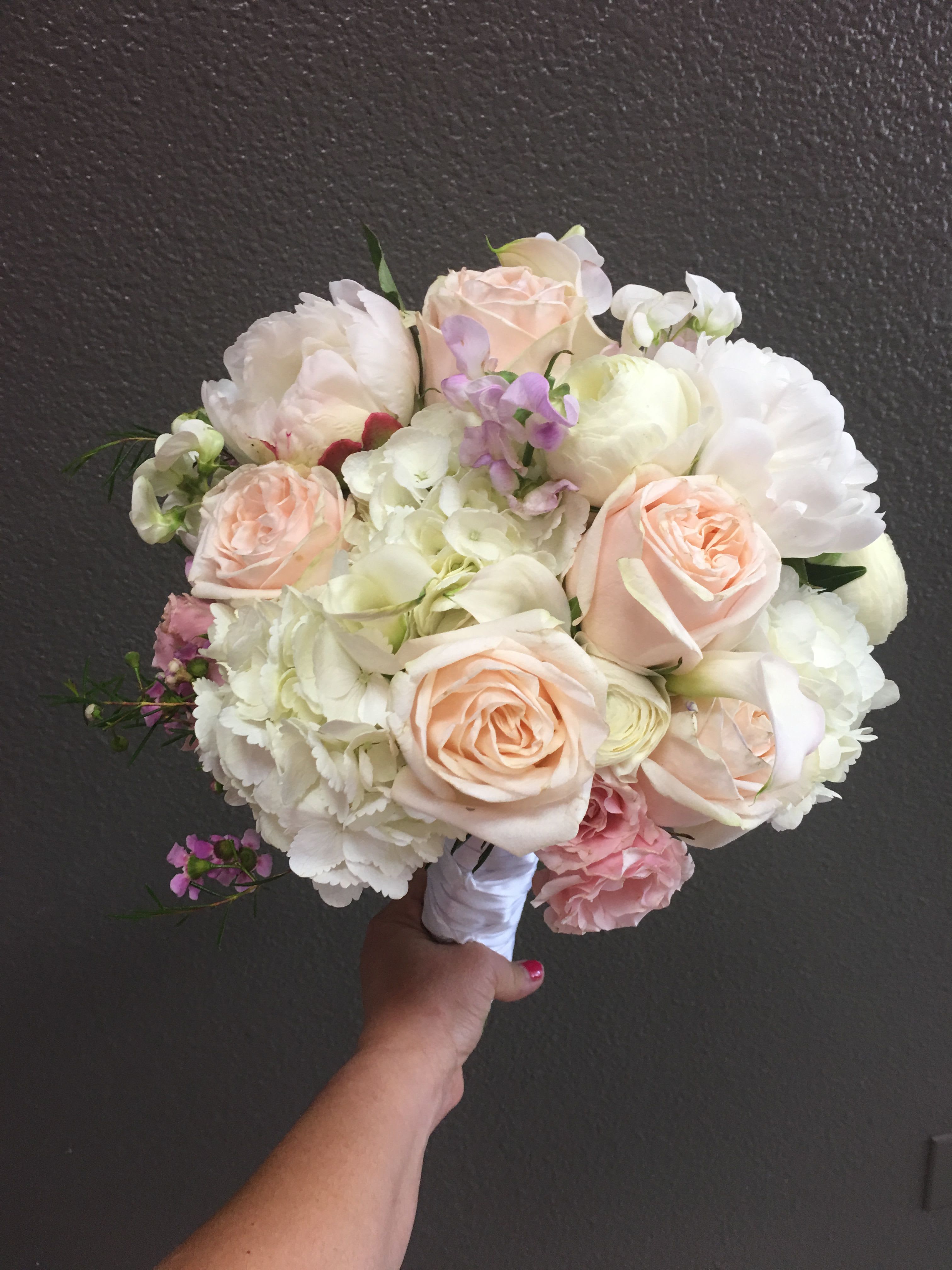 Handheld bouquet of pale pink and white roses with white blooms