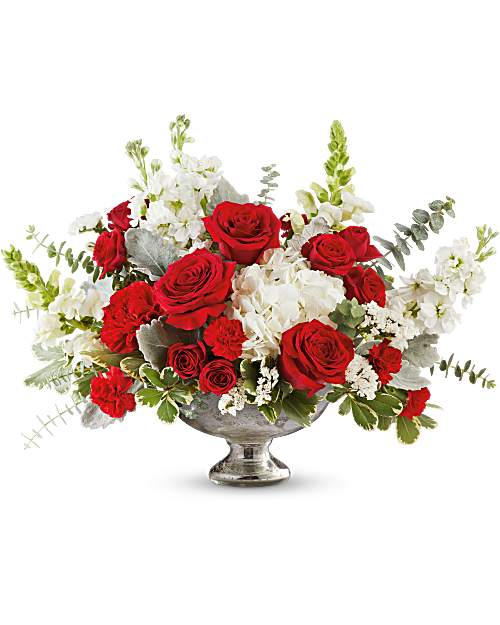 Red roses and white flowers arranged in a silver pedestal vase