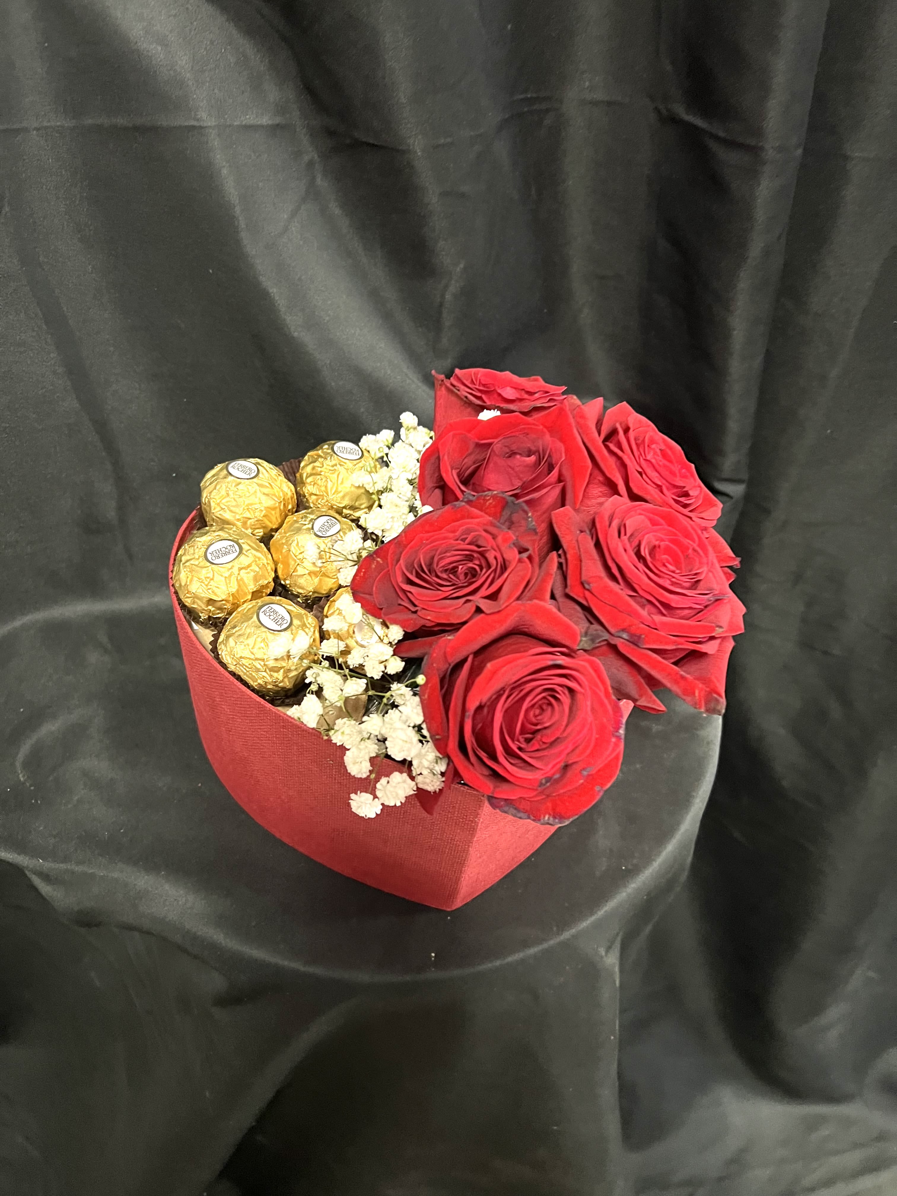 Red roses with gold-wrapped chocolates in a red heart box