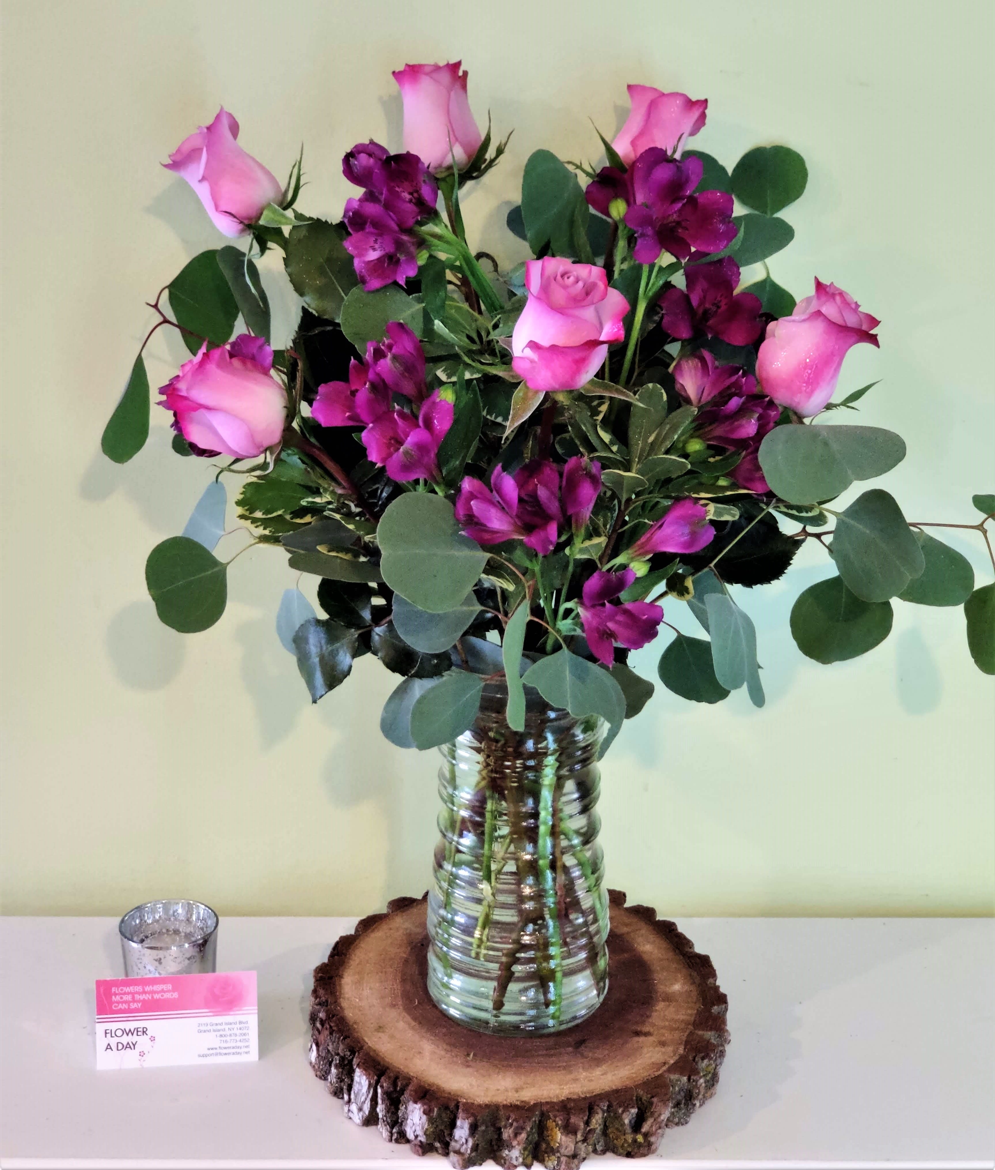 Pink roses and purple flowers arranged in a glass vase