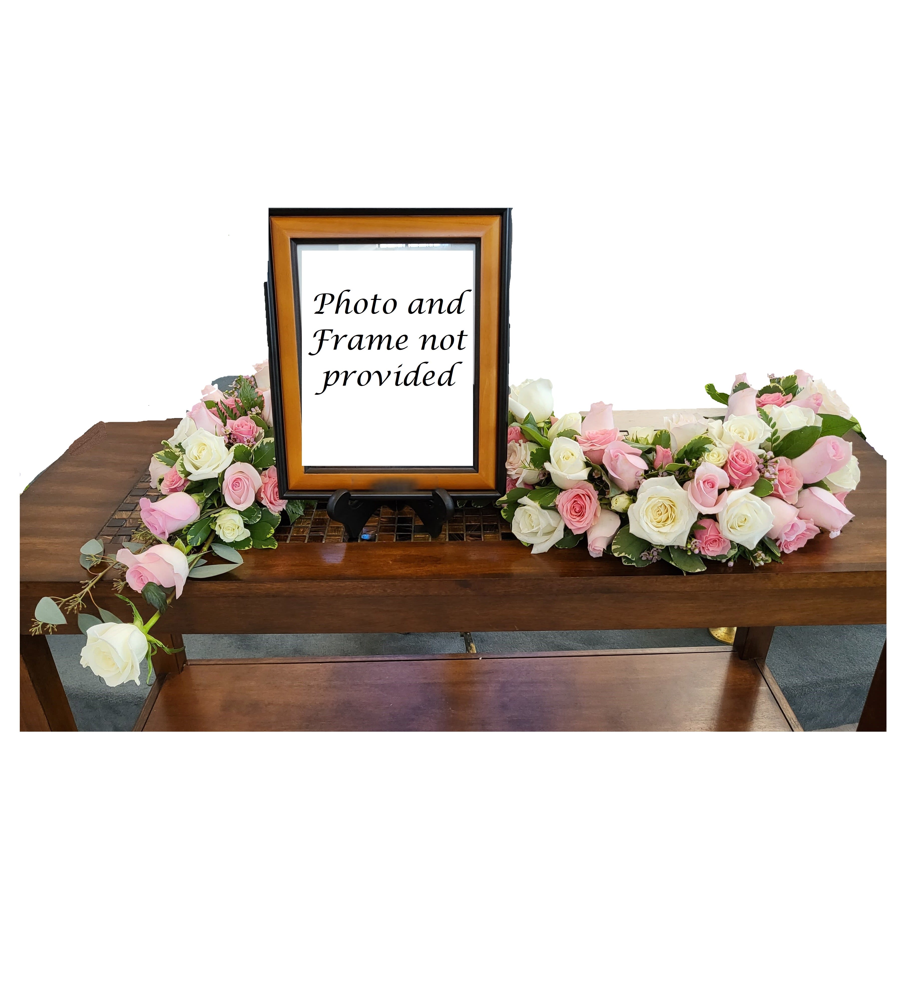 Pink and white rose arrangements flanking a framed sign on a table