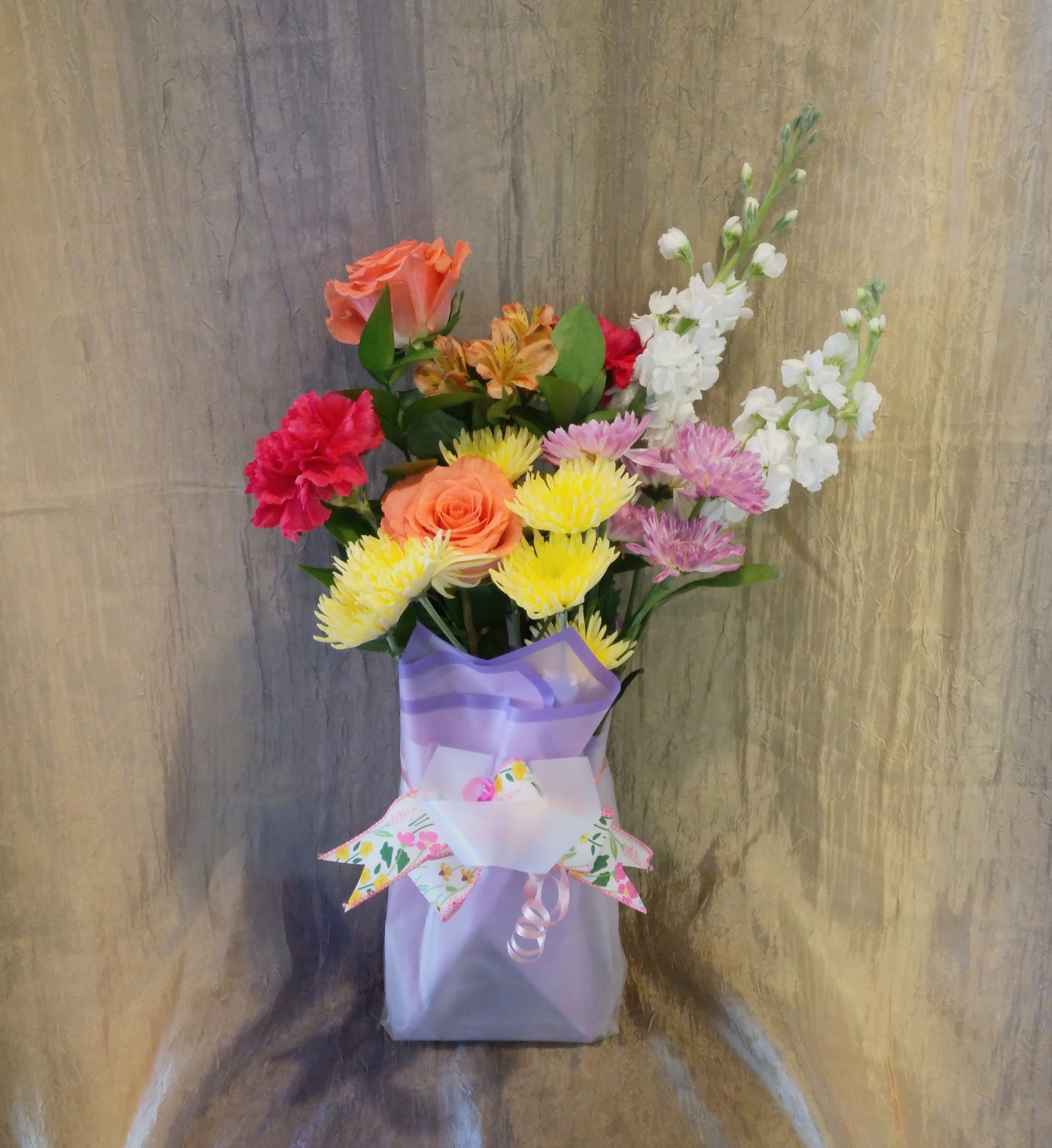 Designer‑In‑Bloom - A thoughtful bundle of blooms presented in a sweet gift bag, created for the recipient who prefers to style their flowers their way. It’s an invitation to snip, shape, and create something uniquely theirs. Colors may vary from photo