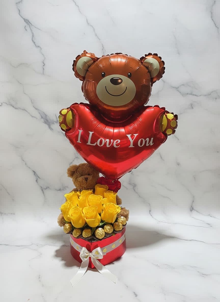 Teddy bear balloon above yellow roses in a red gift box