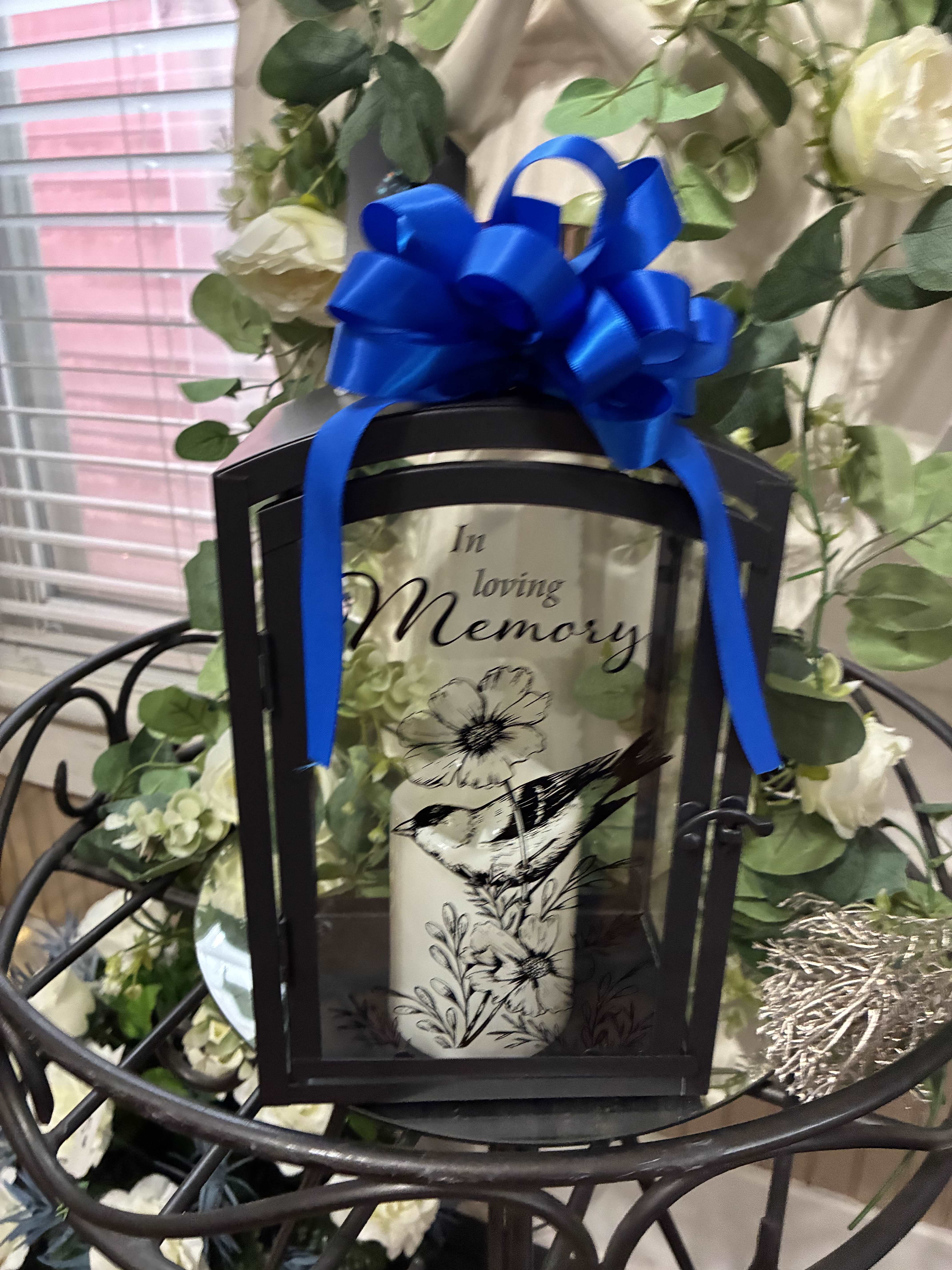 Memorial lantern with a blue bow and white flowers