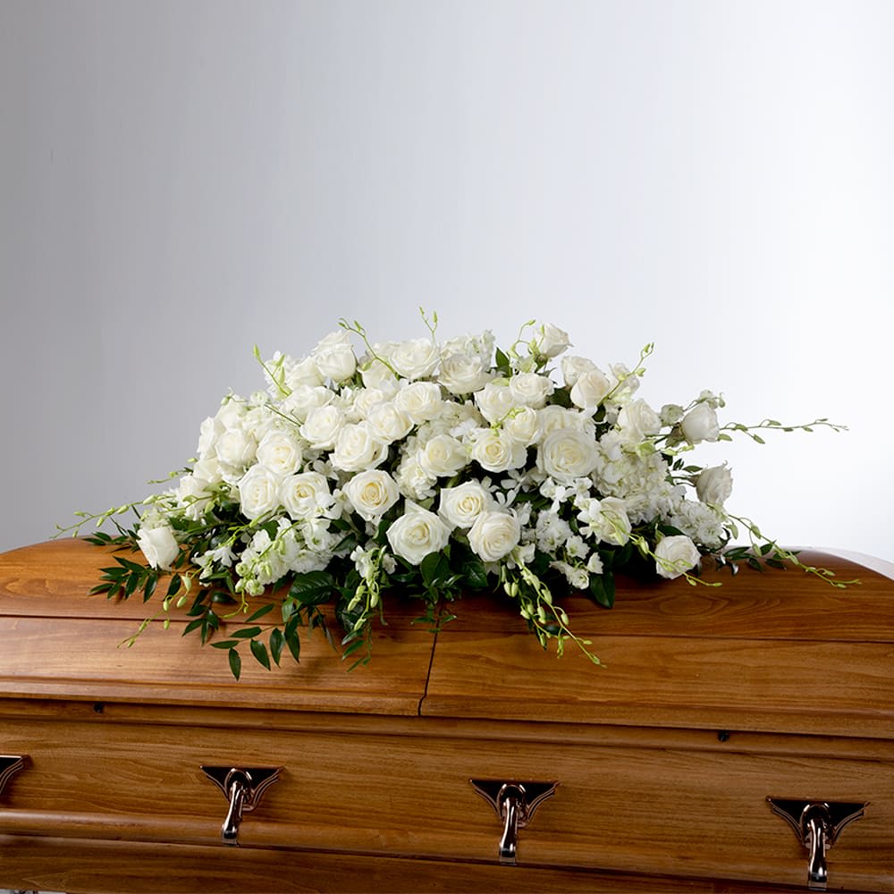 White rose casket spray on a wooden coffin