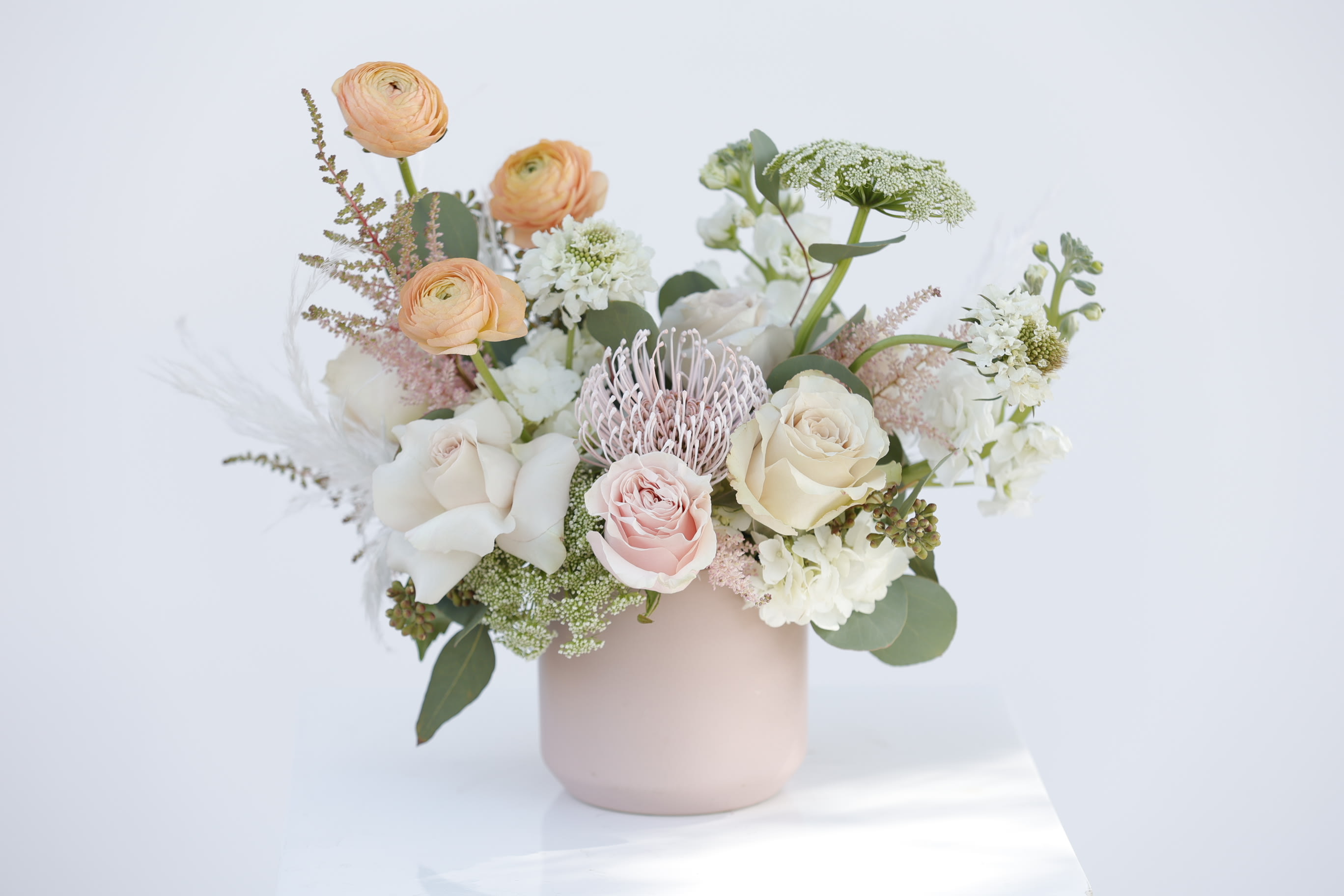 Pastel bouquet of roses and ranunculus in a blush vase