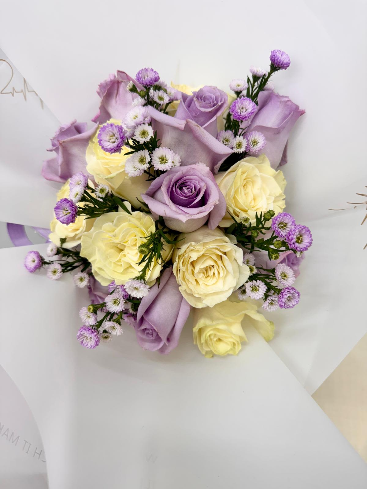 Bouquet of lavender and cream roses with small purple filler flowers