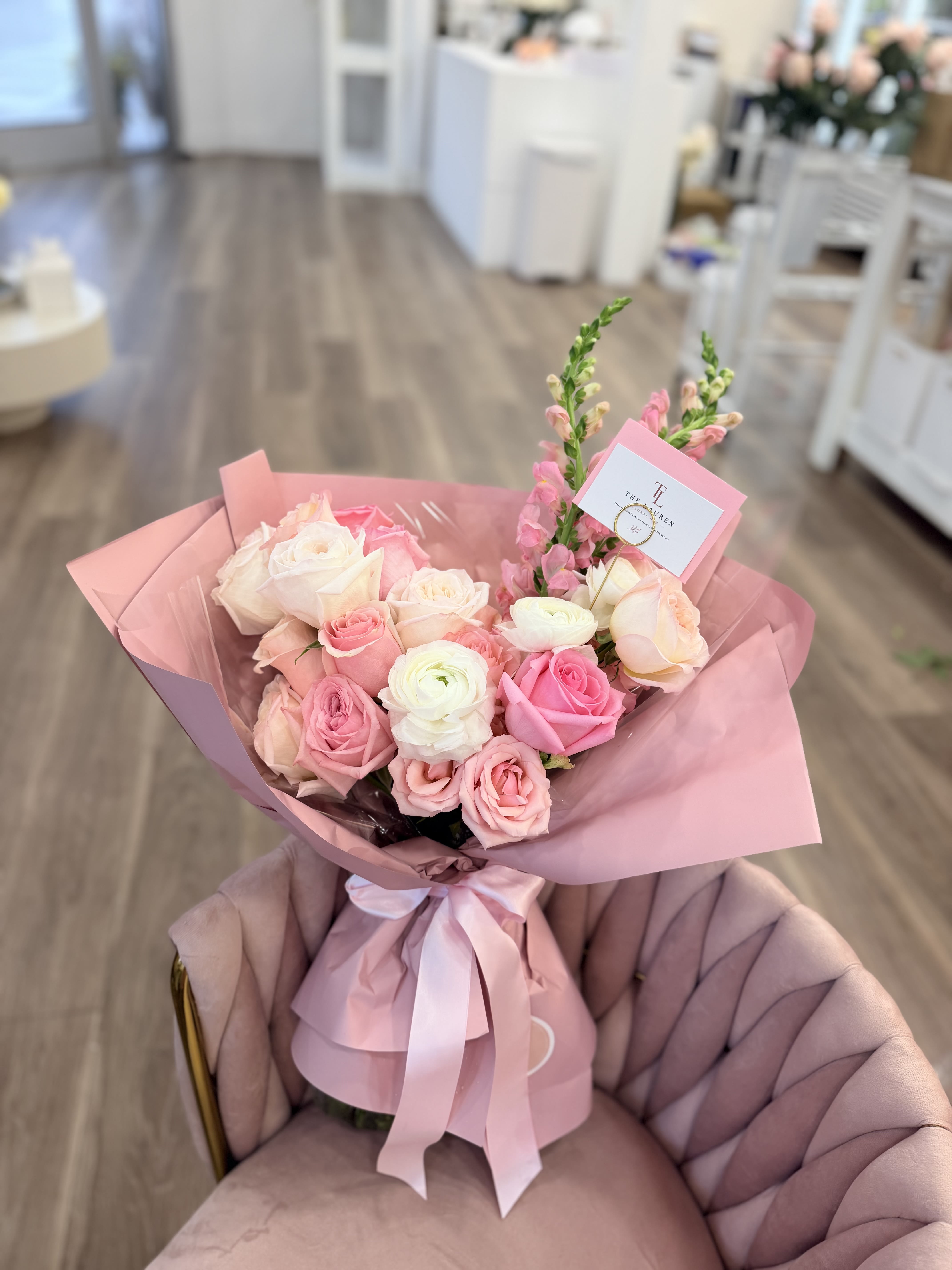 Soft Girl Collection -Rose - A lush, hand-tied bouquet in soft pinks, peach, cream and a touch of lavender-this spring-ready arrangement is a warm, feminine way to say "thank you." Rounded clusters of roses and layered ranunculus-like blooms create a full, romantic centerpiece while upright snapdragons and spiky purple accents add gentle vertical movement. The overall impression is elegant and celebratory, perfect for thanking someone special or marking congratulations, birthdays, anniversaries, or Mother's Day.  Filled with roses, calla lilies, lisianthus, ranunculus-style blooms and airy filler, the bouquet is wrapped in layered matte pink and decorative paper and finished with a pale satin ribbon and a floral card for your message. The finish includes a polished paper wrap and wide ribbon for a gift-ready presentation; textures range from glossy calla petals to the soft, velvety rose petals for a tactile contrast recipients will notice. Order in time for spring deliveries or any season when you want the person you're thinking of to feel truly seen and celebrated.
