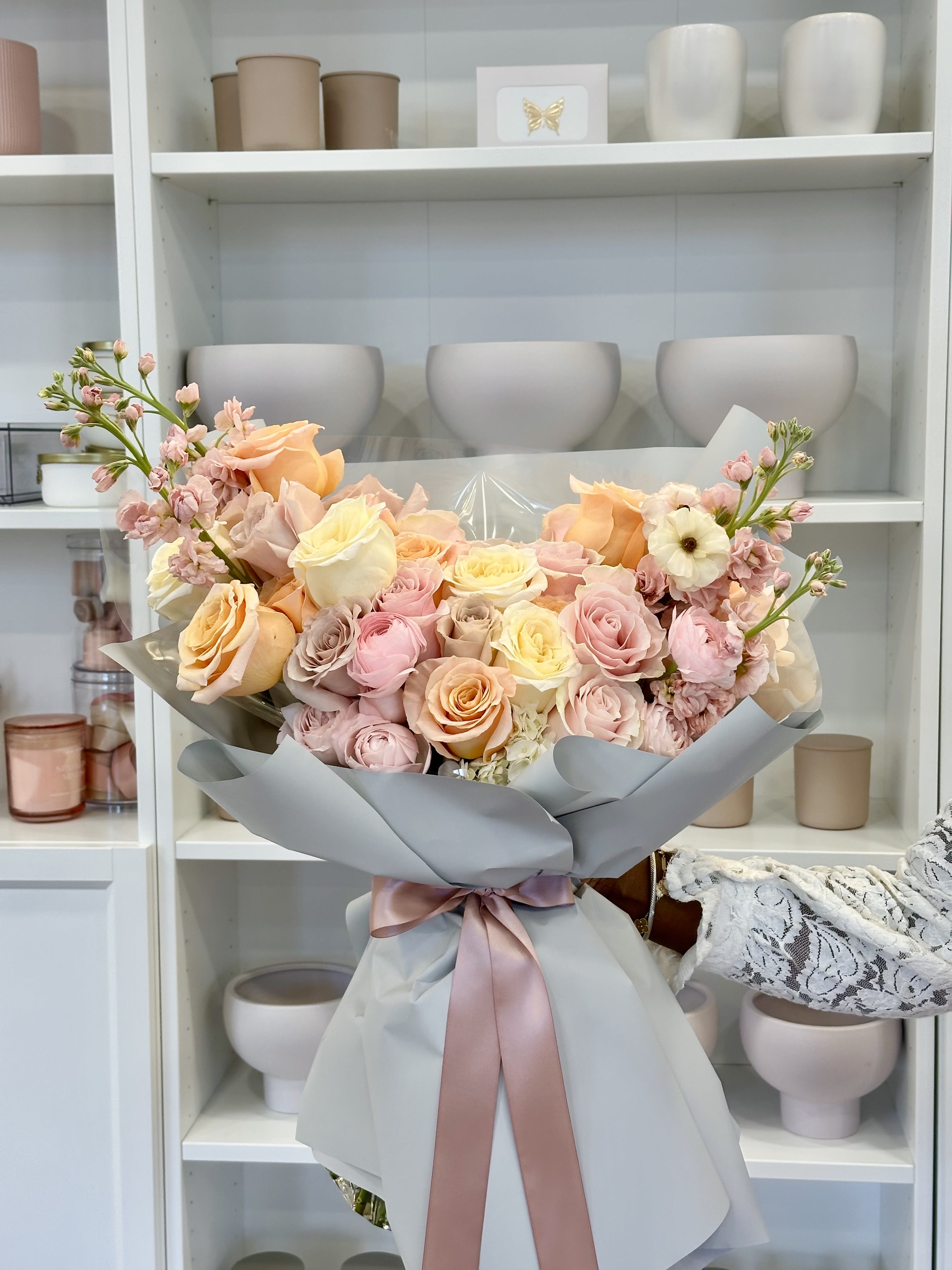 The Lauren - Lush hand-tied bouquet of pastel roses , spray roses ,ranunculus and stock in pink, peach, white wrapped with satin ribbon