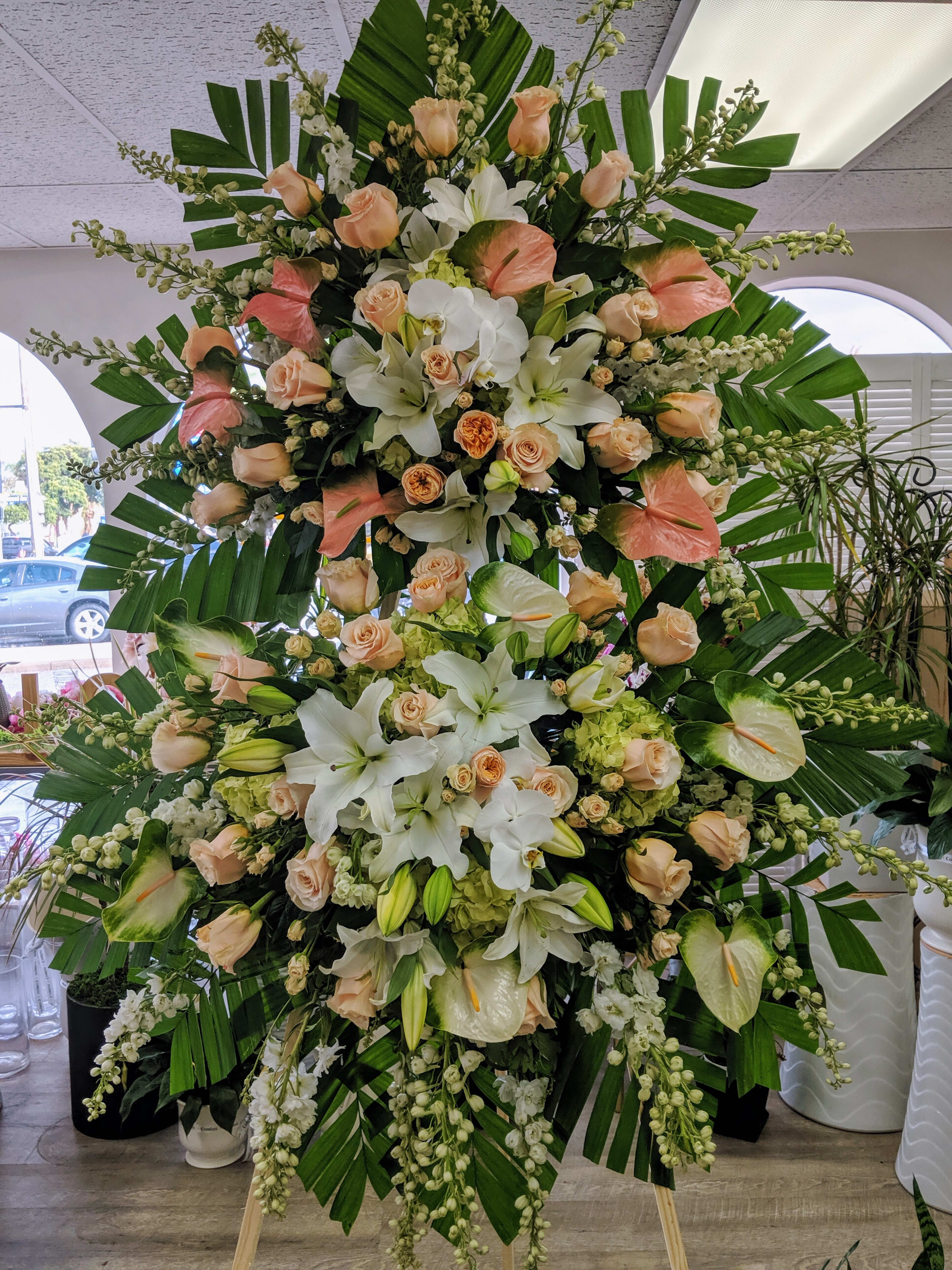 Large standing floral spray with white lilies, peach roses, and anthuriums