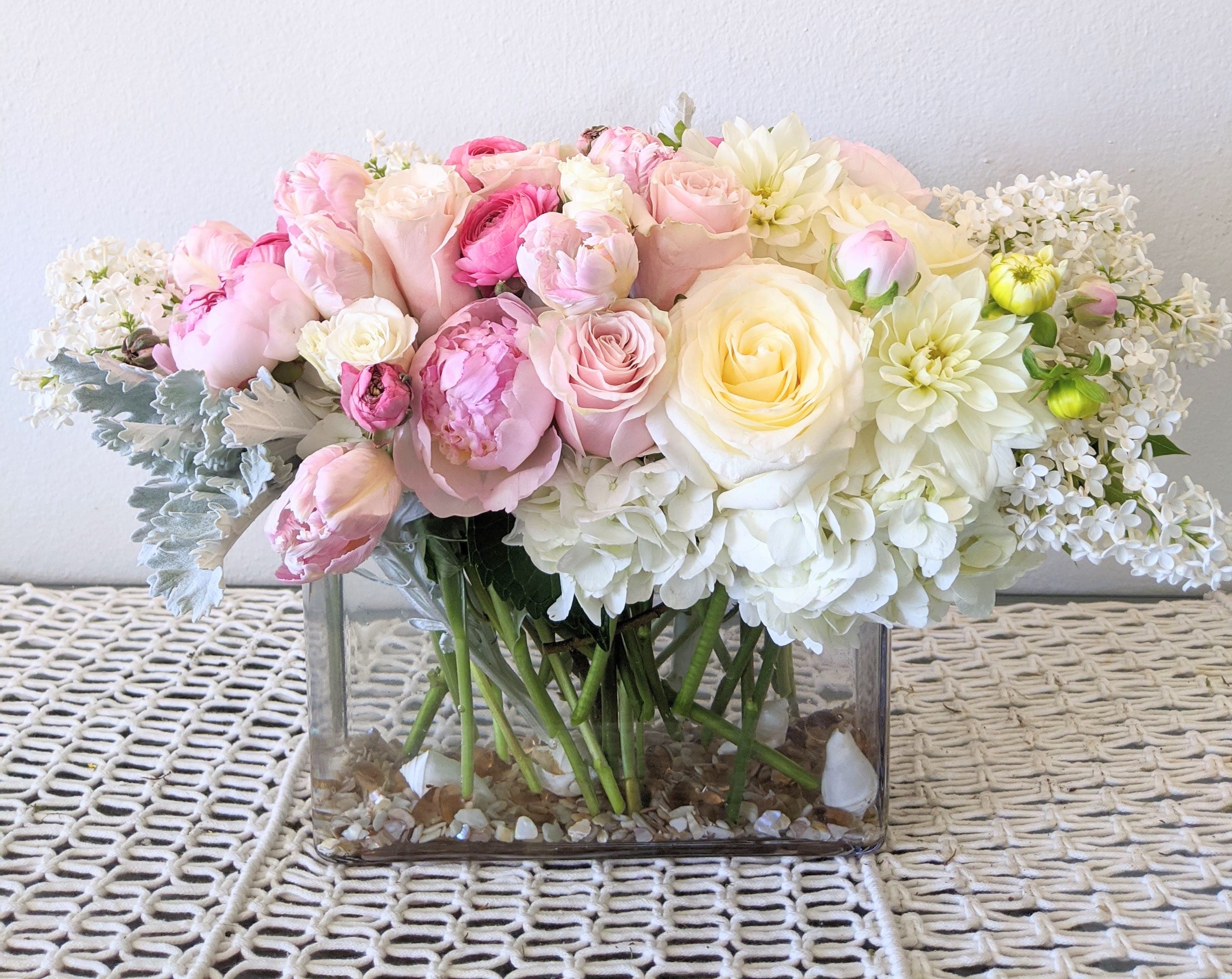 Pink and white flower arrangement in a clear rectangular vase