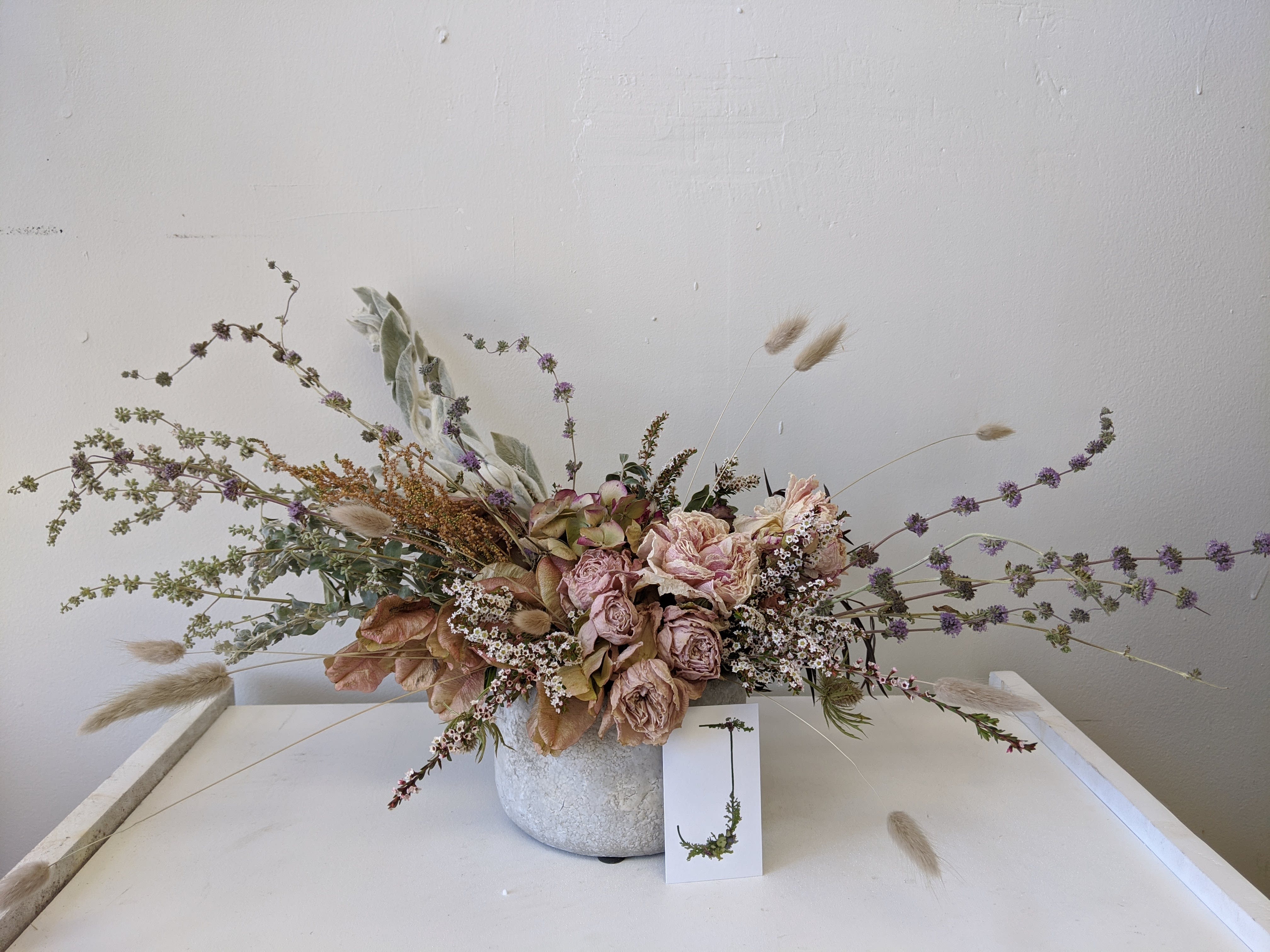 Everlasting Centerpiece- Ceramic - This everlasting dried arrangement includes dried Peonies and comes in a cement like stone pot. Business card in photo for scale. Note that because of the nature of dried flowers, some may break and crumble if not carefully handled.