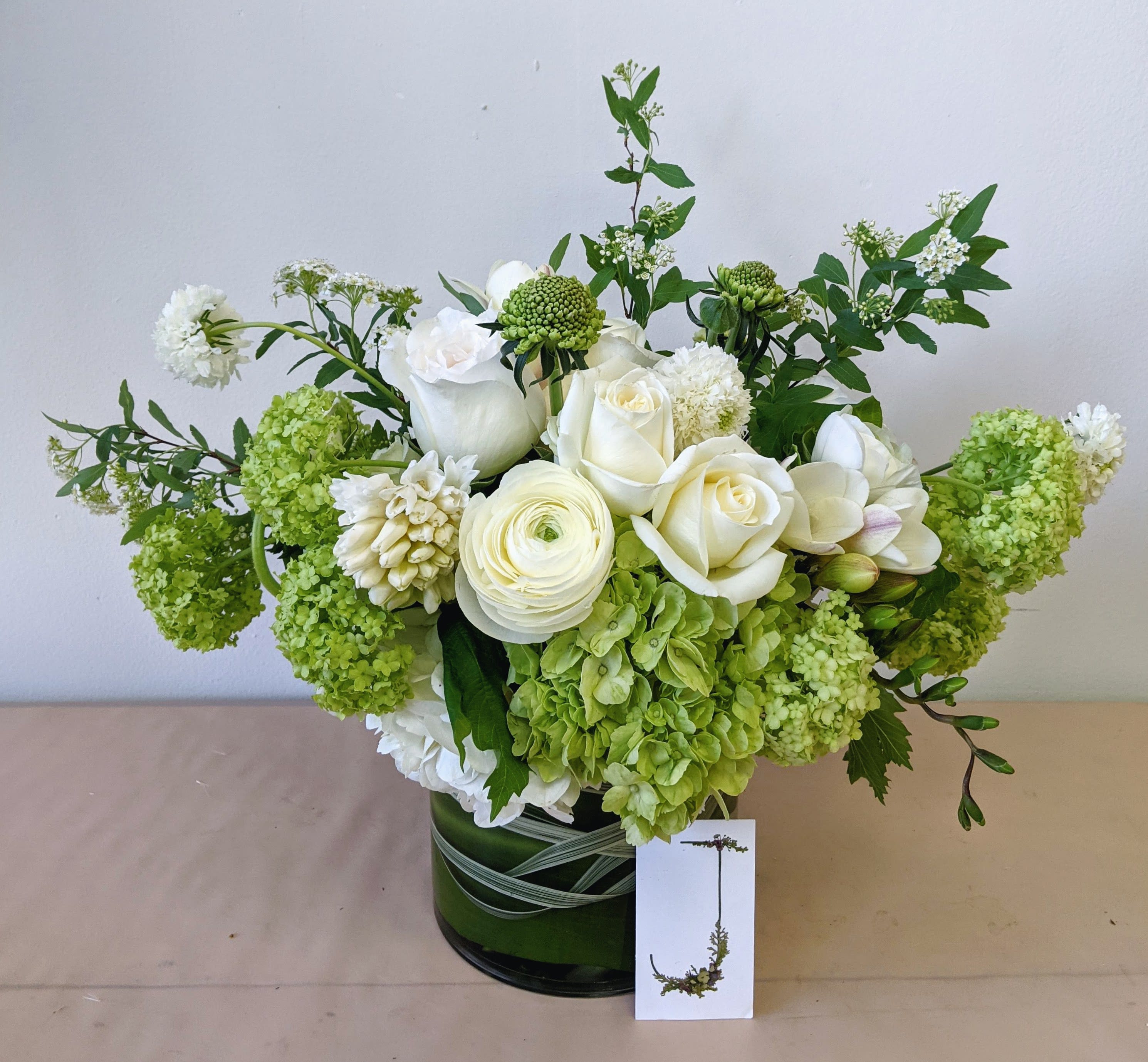 White and green floral arrangement in a dark glass vase
