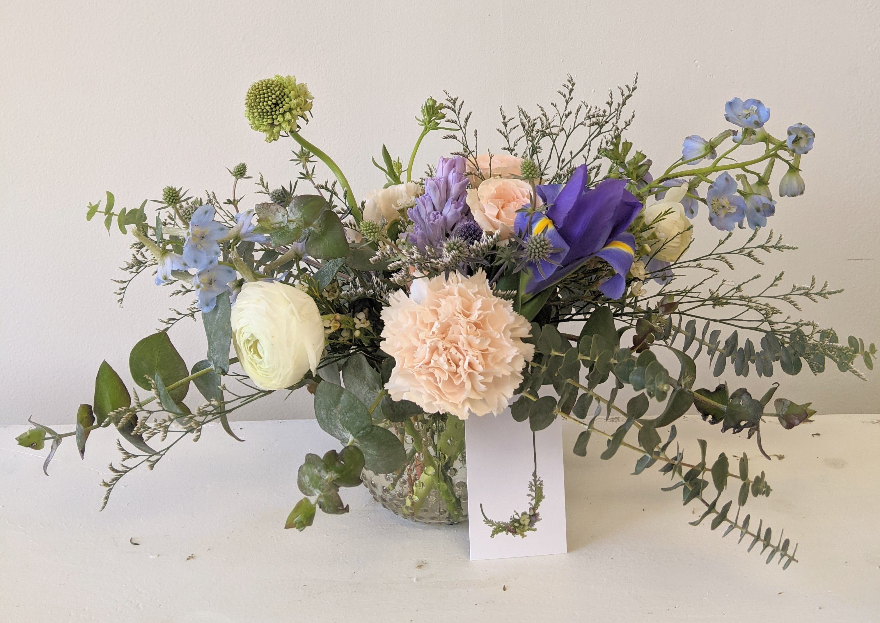 Mixed bouquet in a glass vase with blue, peach, and white flowers
