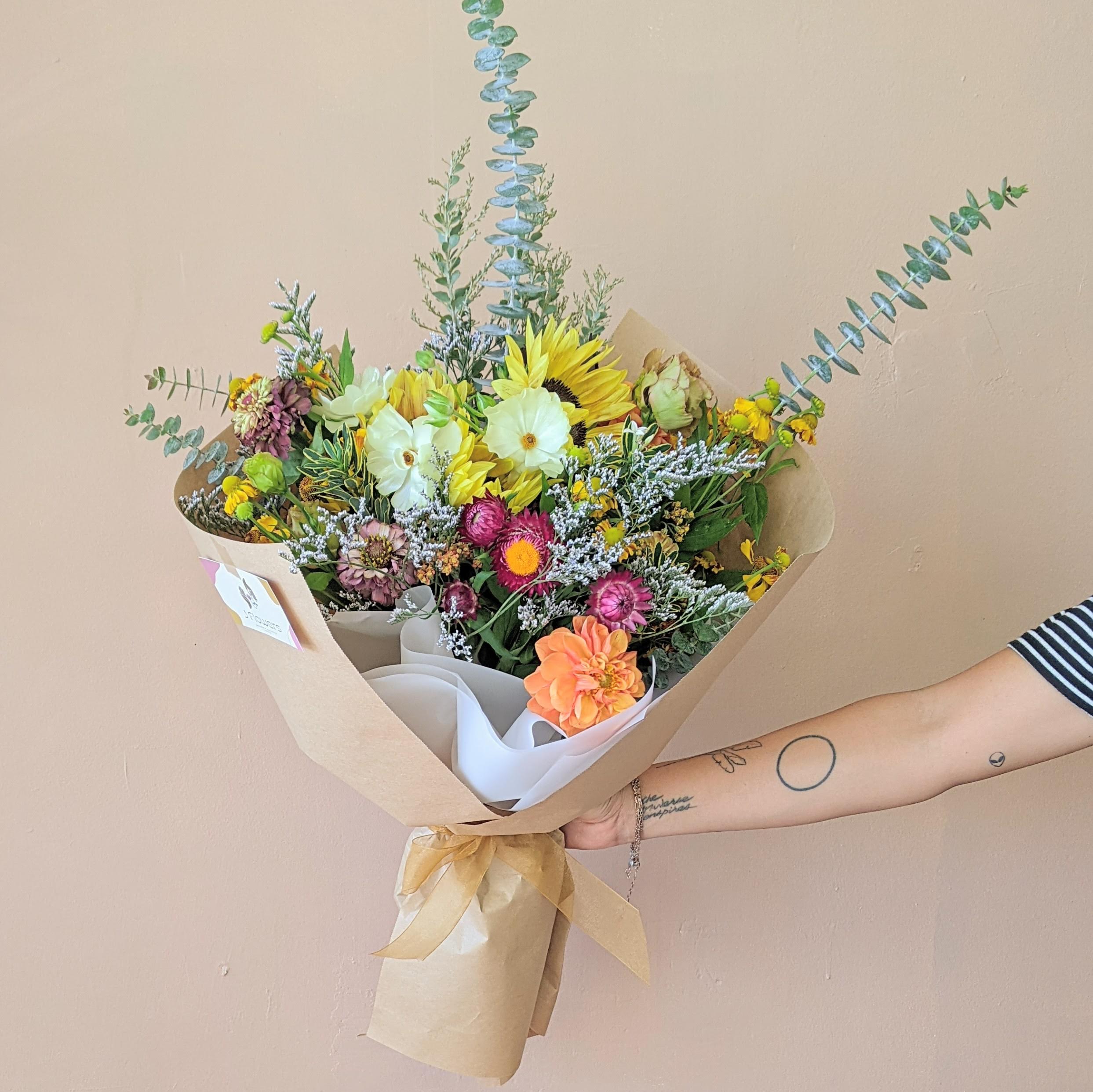 Hand-tied bouquet with sunflowers and mixed blooms in kraft paper