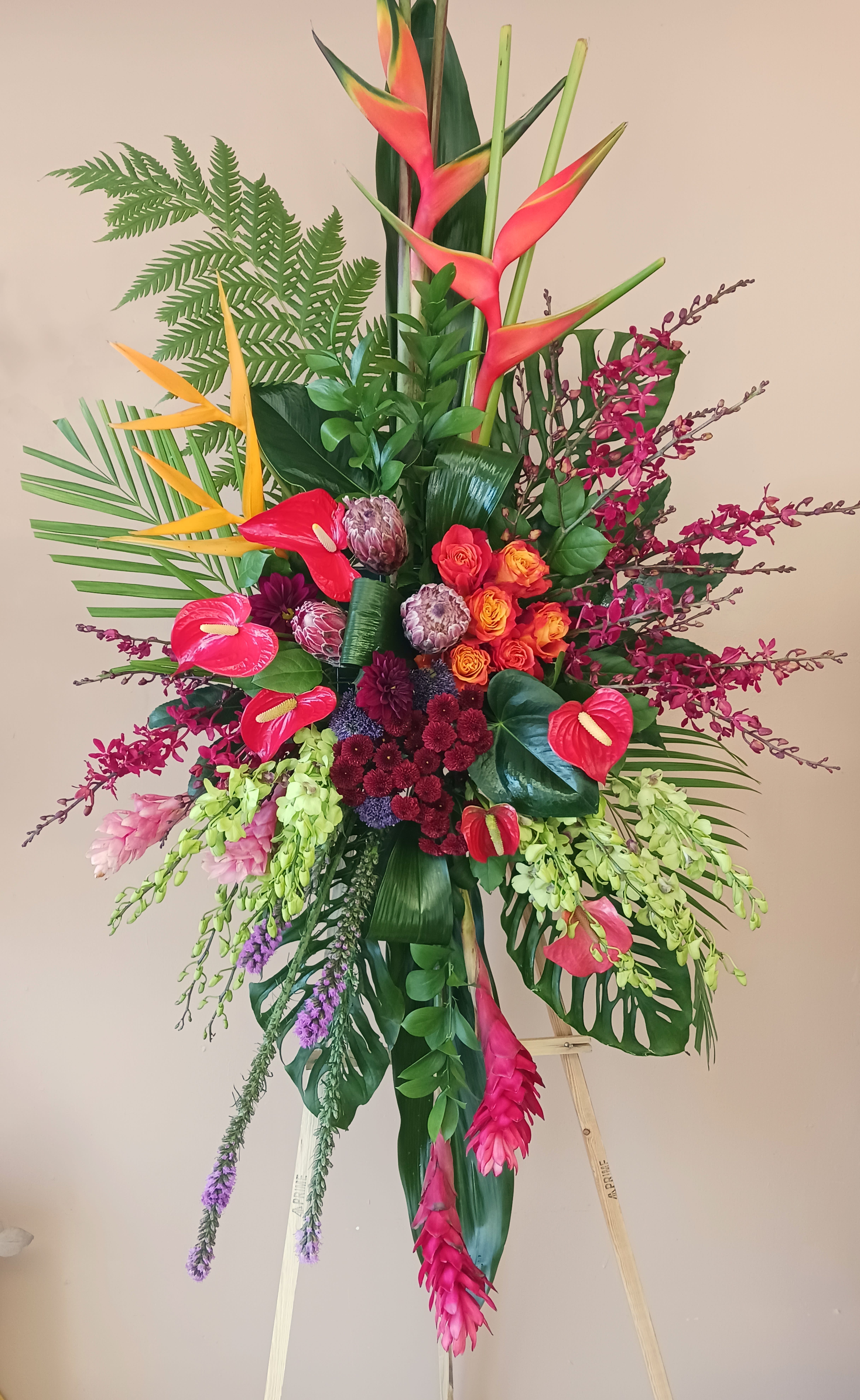 Tall tropical floral arrangement with orchids, anthuriums, and birds of paradise