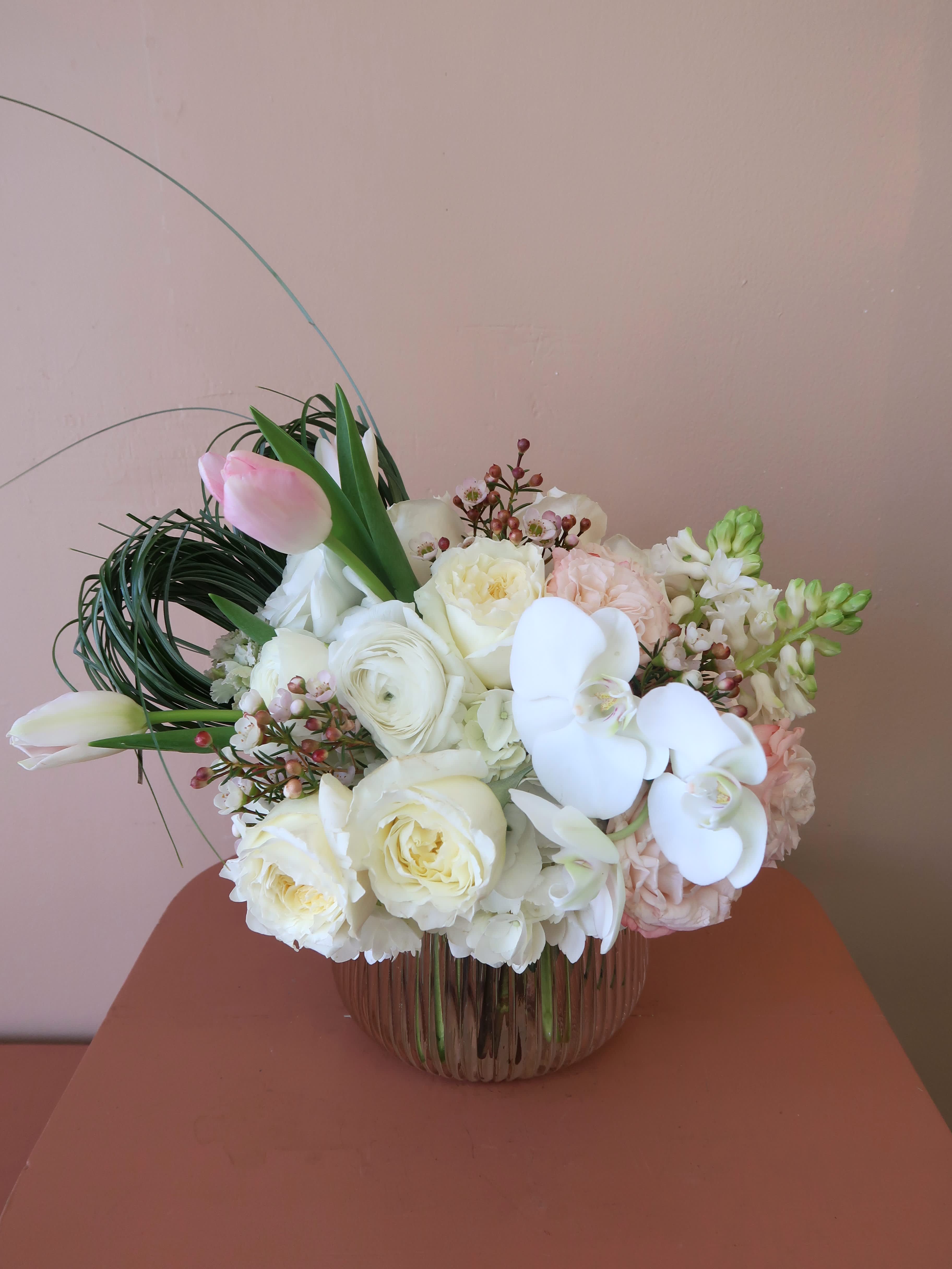 White and blush bouquet with orchids and roses in a glass vase