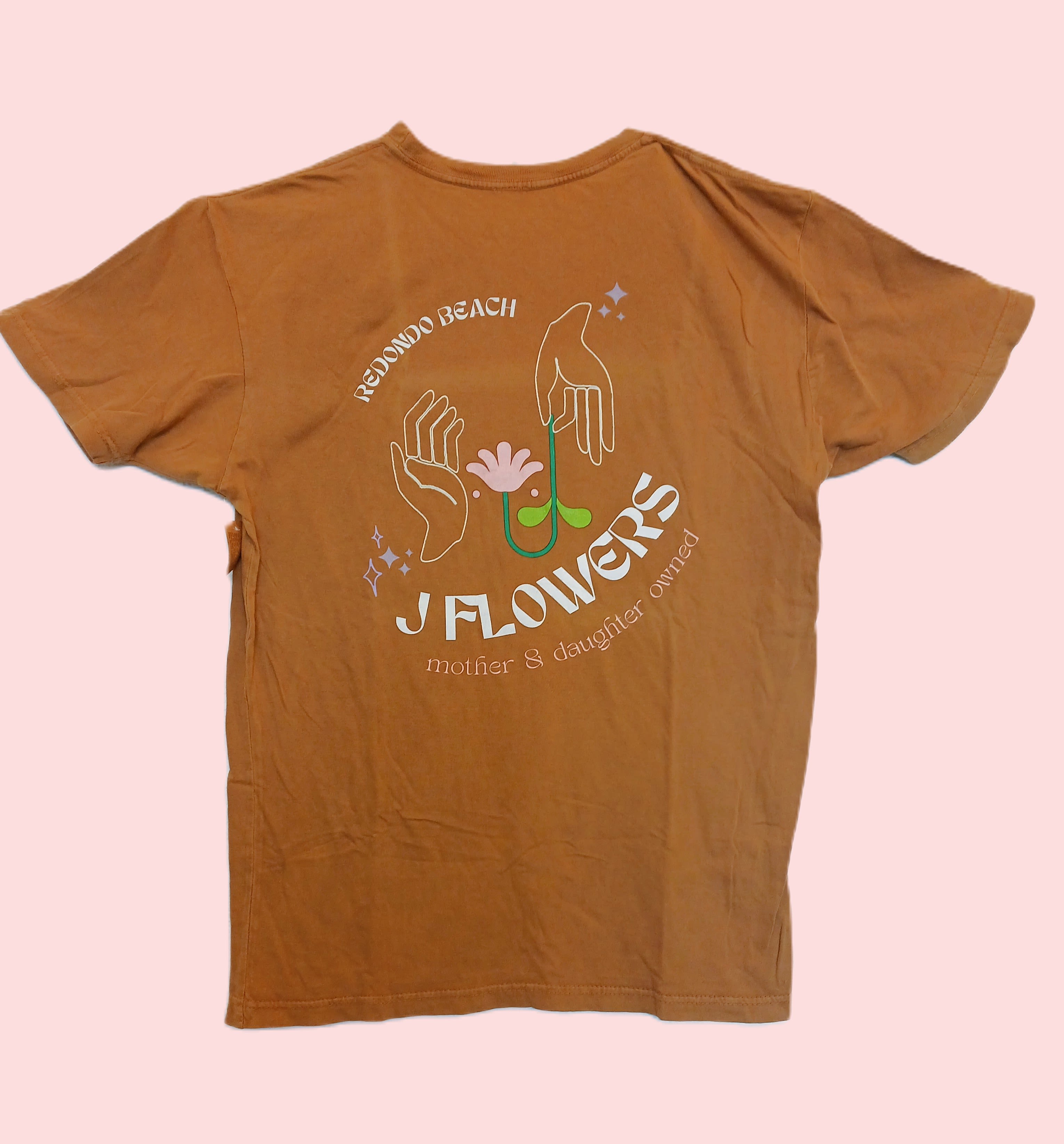 Brown graphic T-shirt with a floral hand illustration and text
