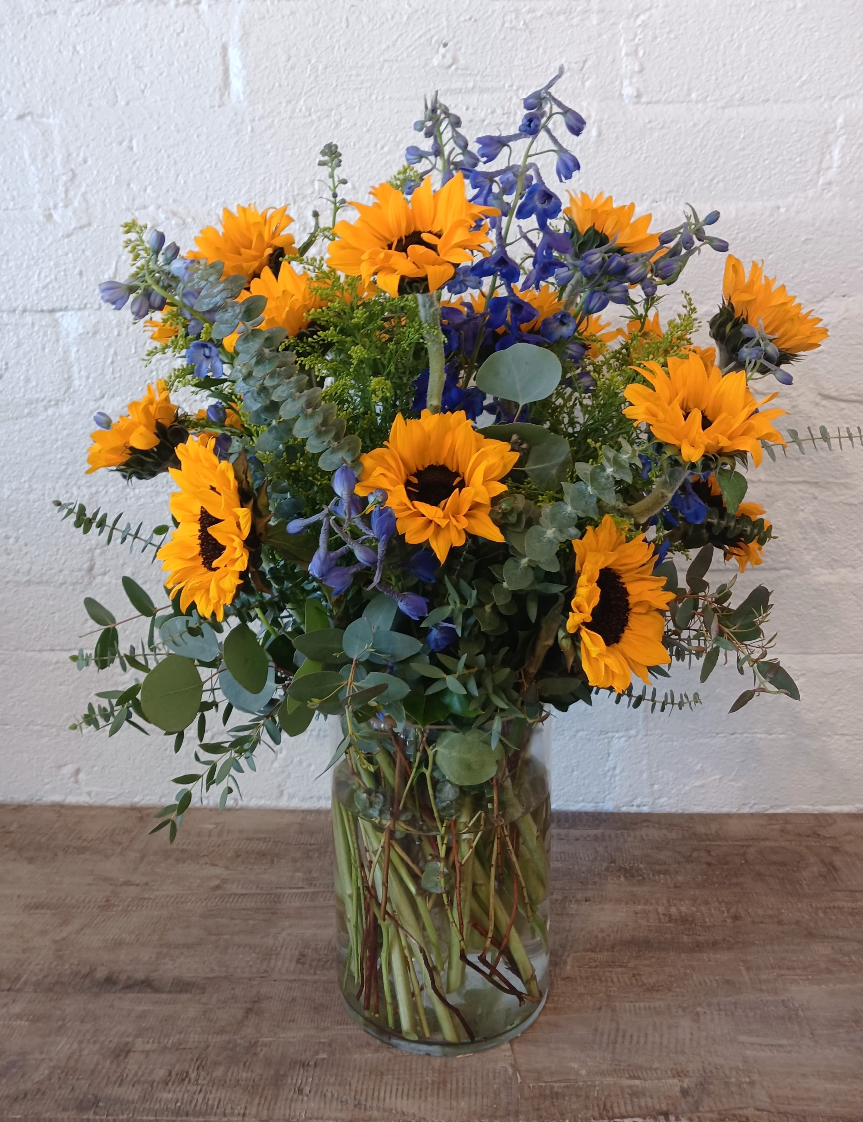 Sunflowers and blue flowers in a clear glass vase