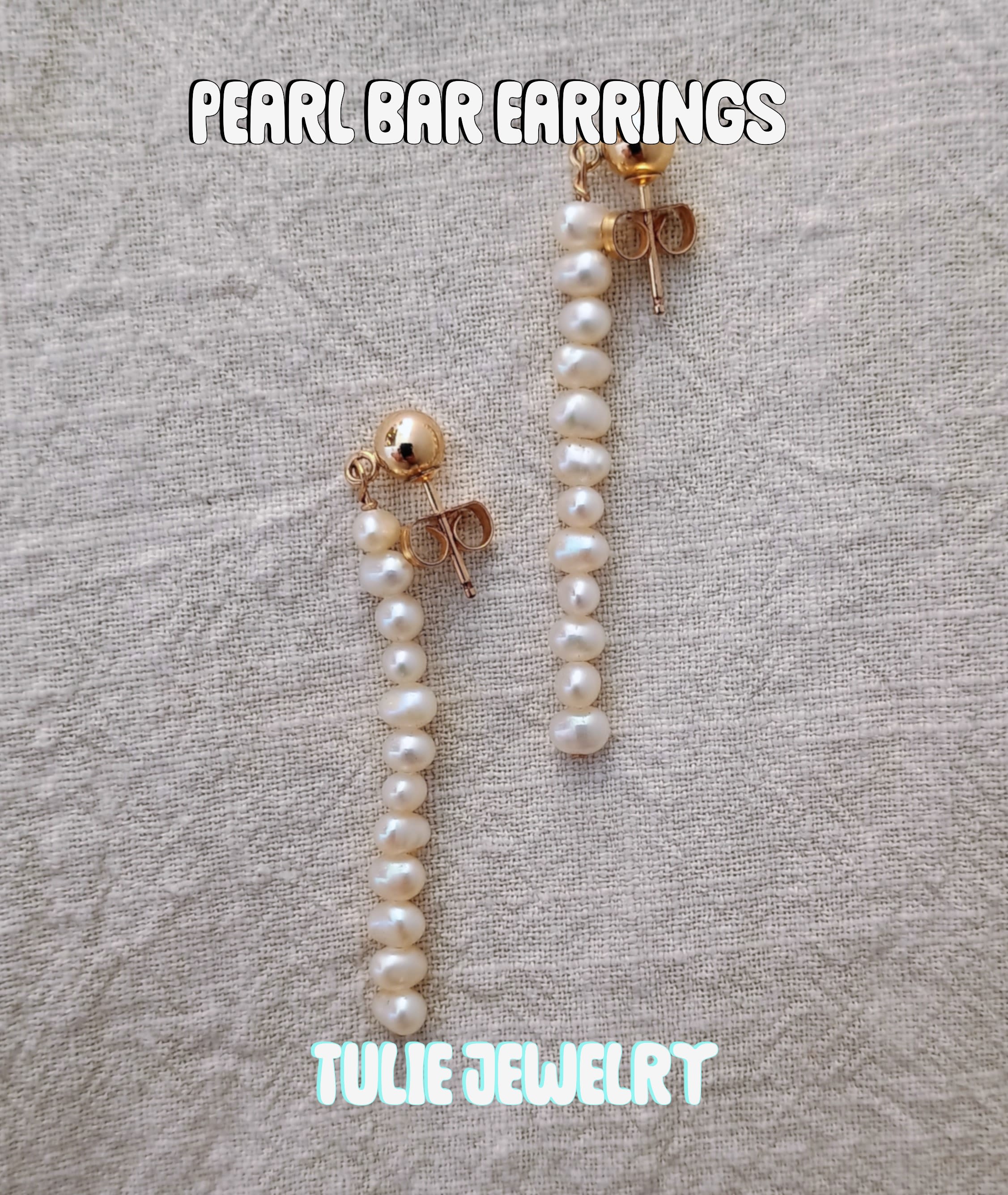 Pair of pearl drop earrings on a textured fabric background