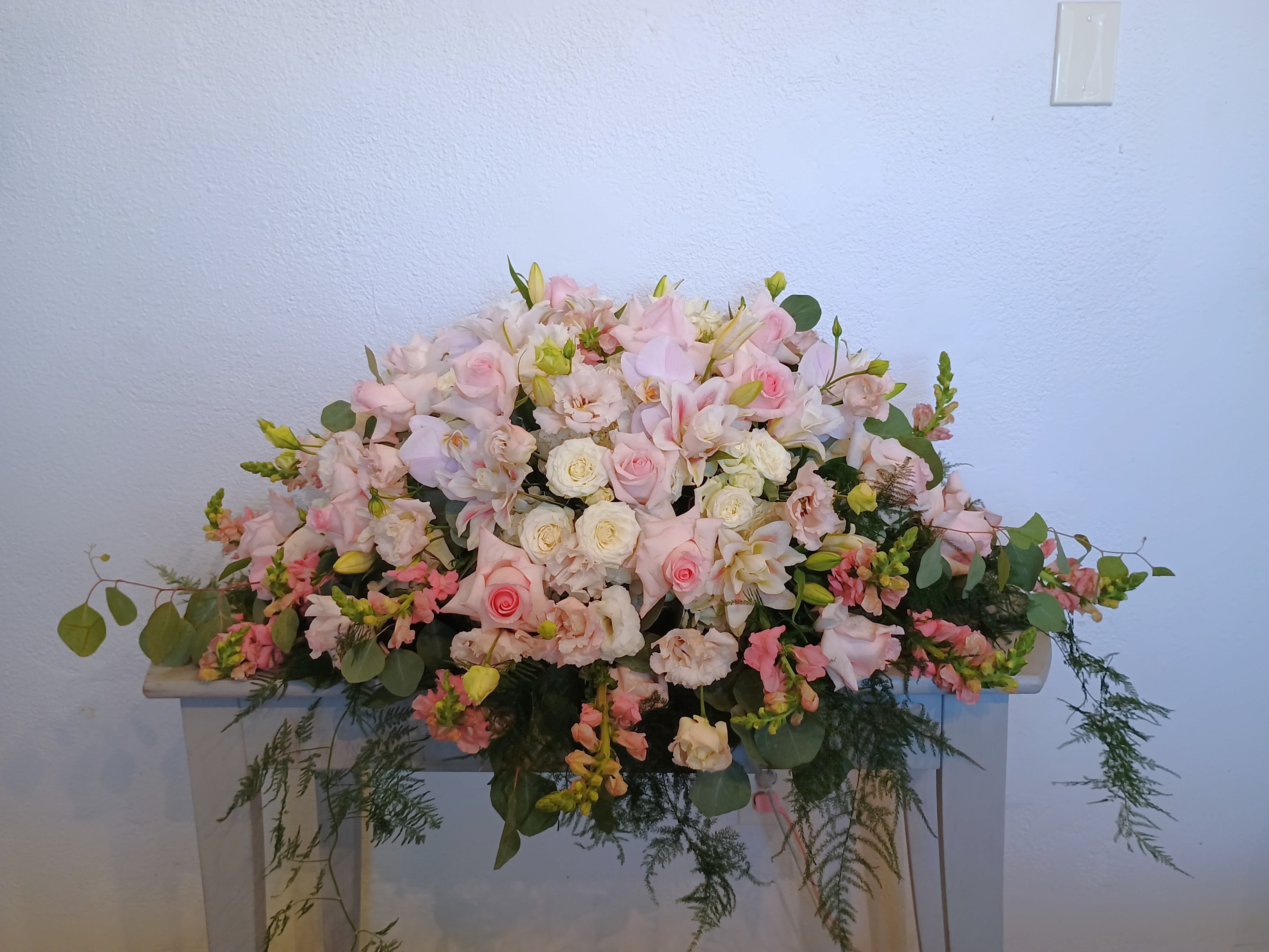 Large pastel floral arrangement with pink and white blooms on a table
