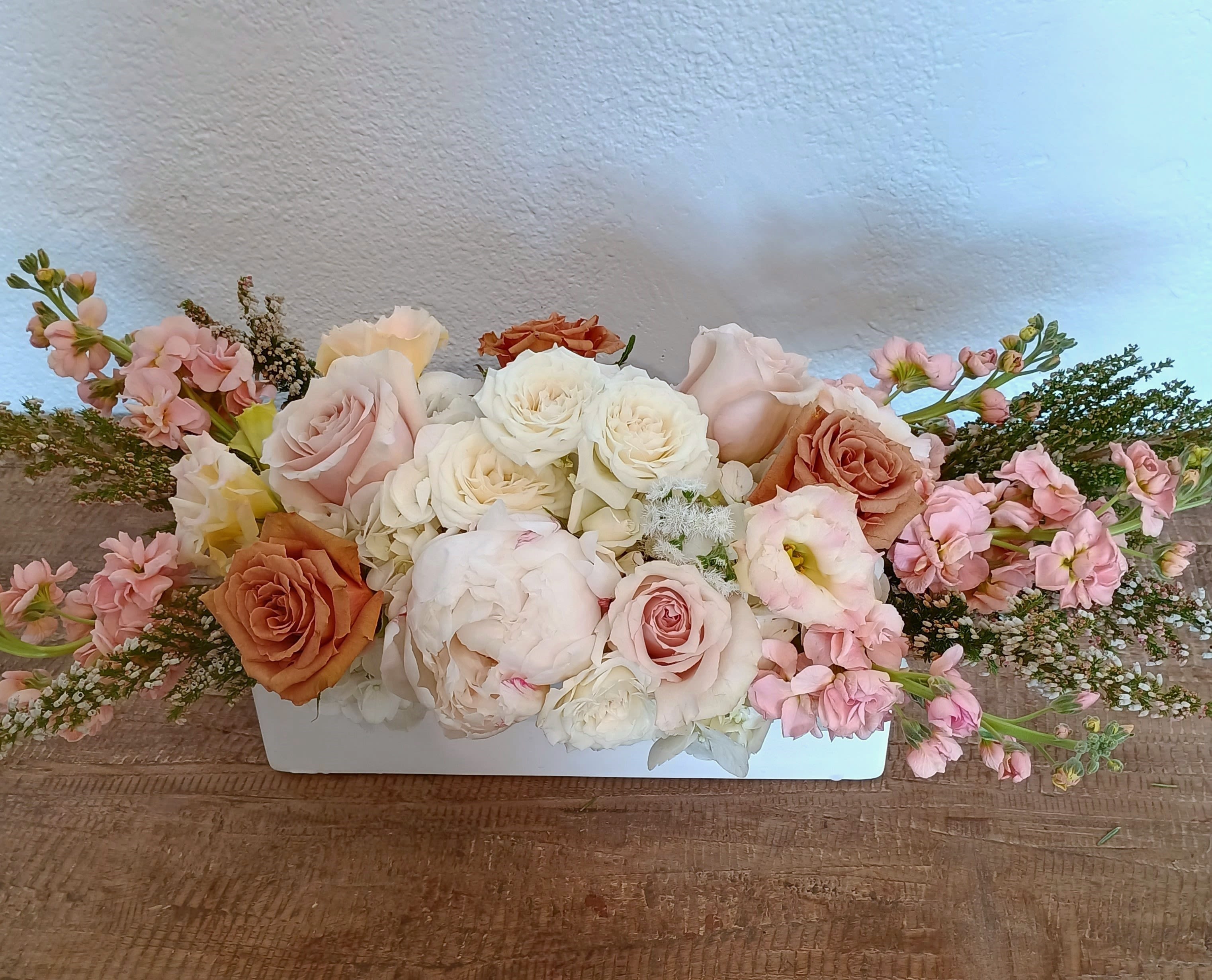 Low floral arrangement of pink and white roses in a white container