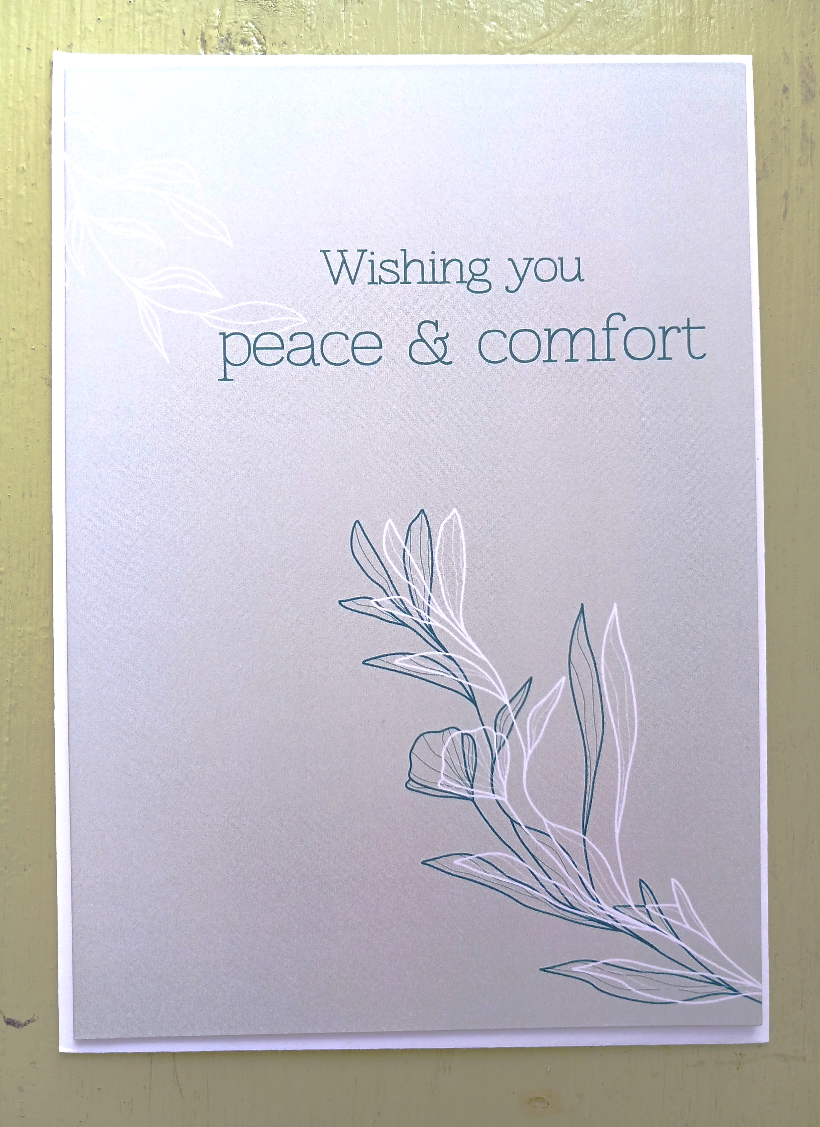 Sympathy greeting card with 'Wishing you peace &amp; comfort' text and simple leaf line art on a soft gray background