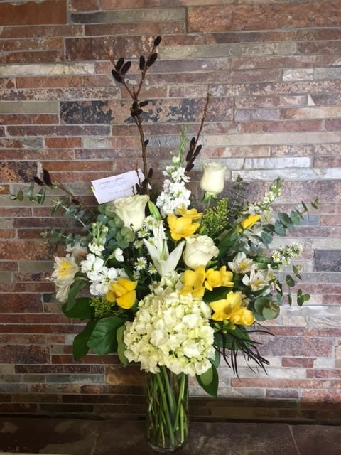 Tall bouquet of white and yellow flowers in a glass vase