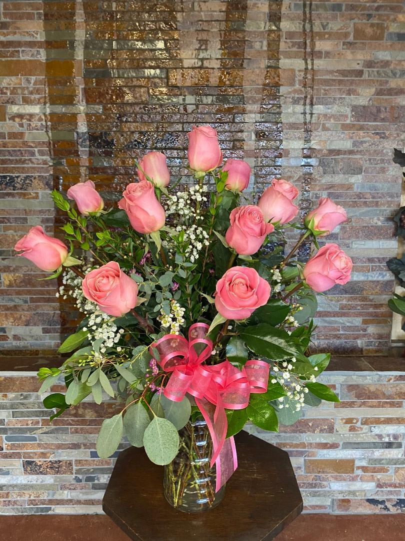 Pink roses in a clear glass vase with a pink ribbon