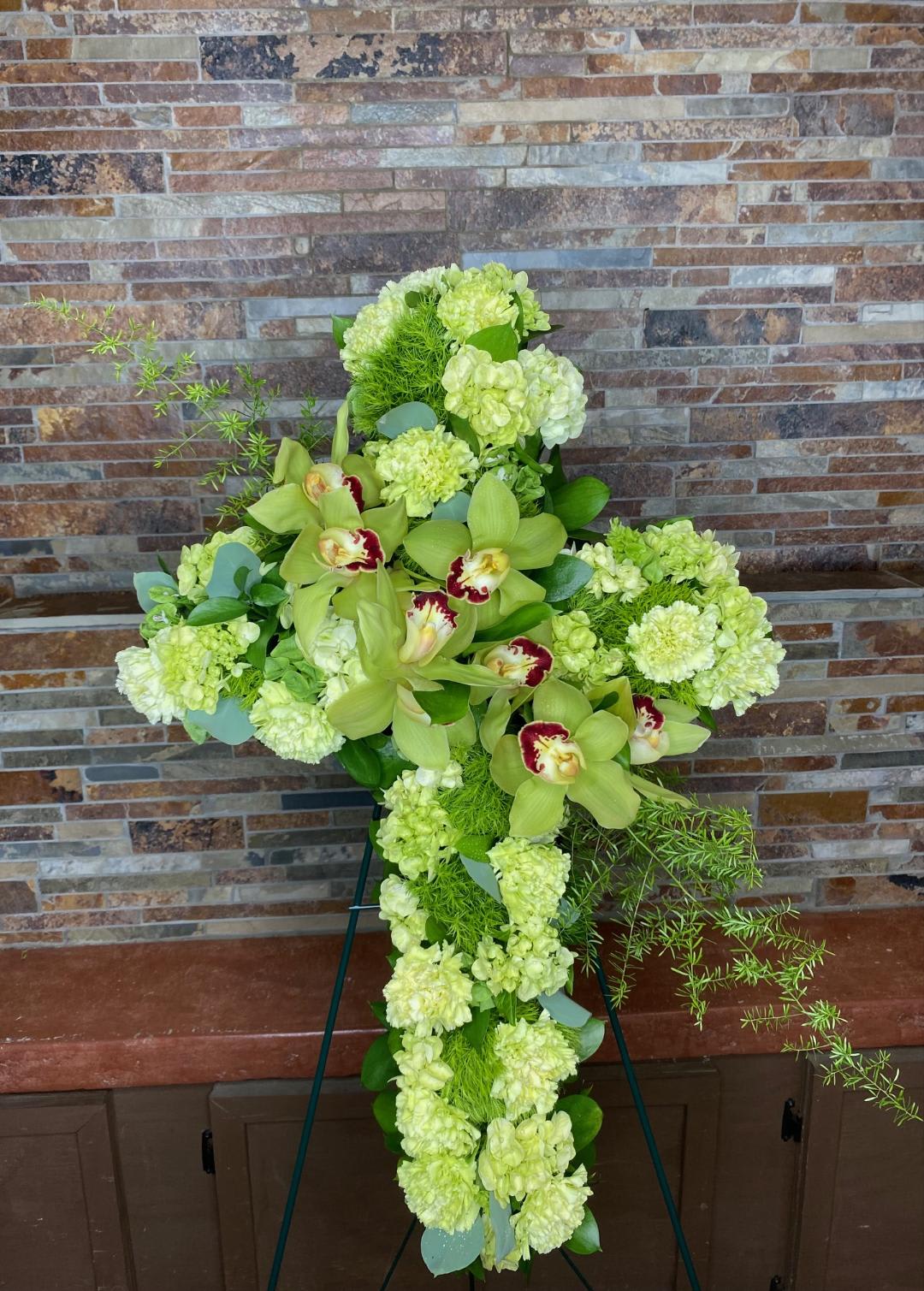 Green floral cross with orchids and pale blooms on an easel