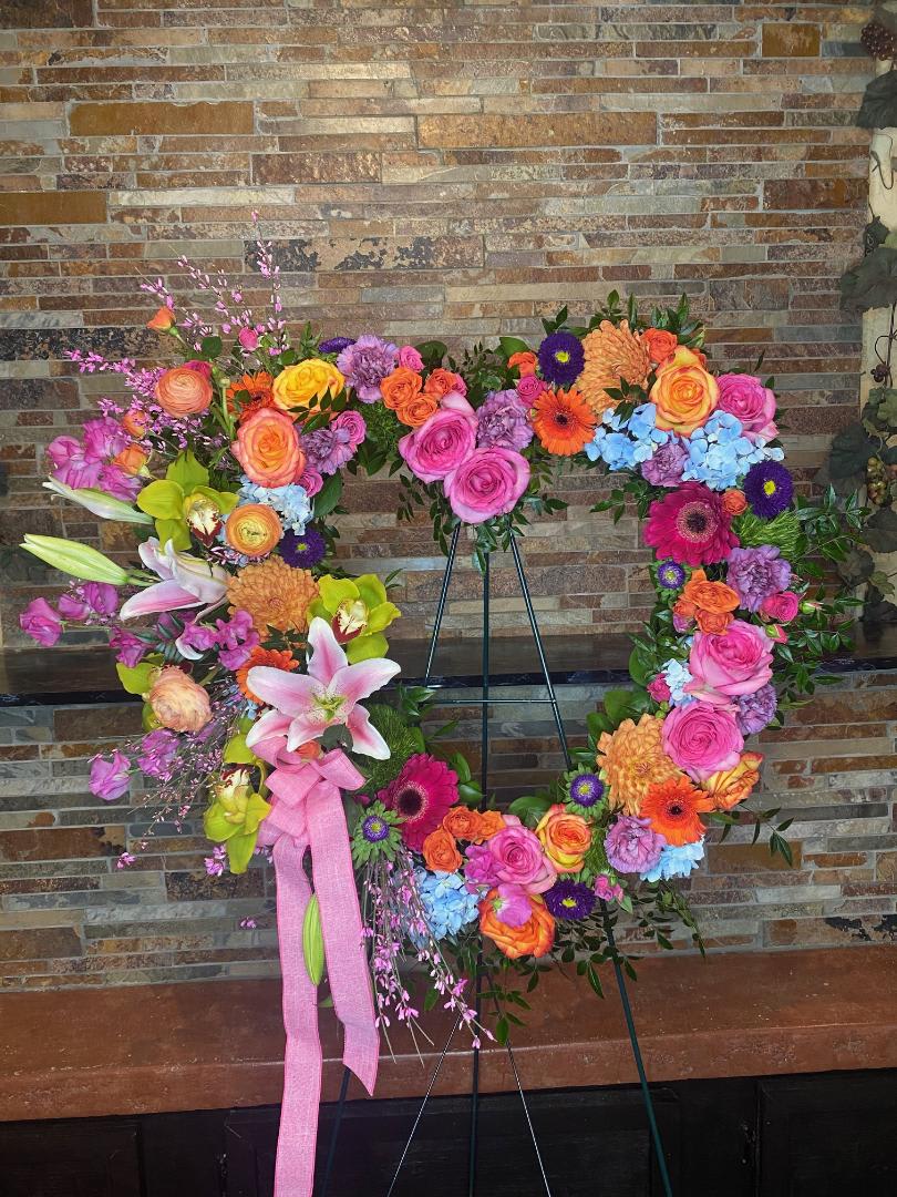 Large floral wreath on an easel with pink, orange, yellow, and blue blooms